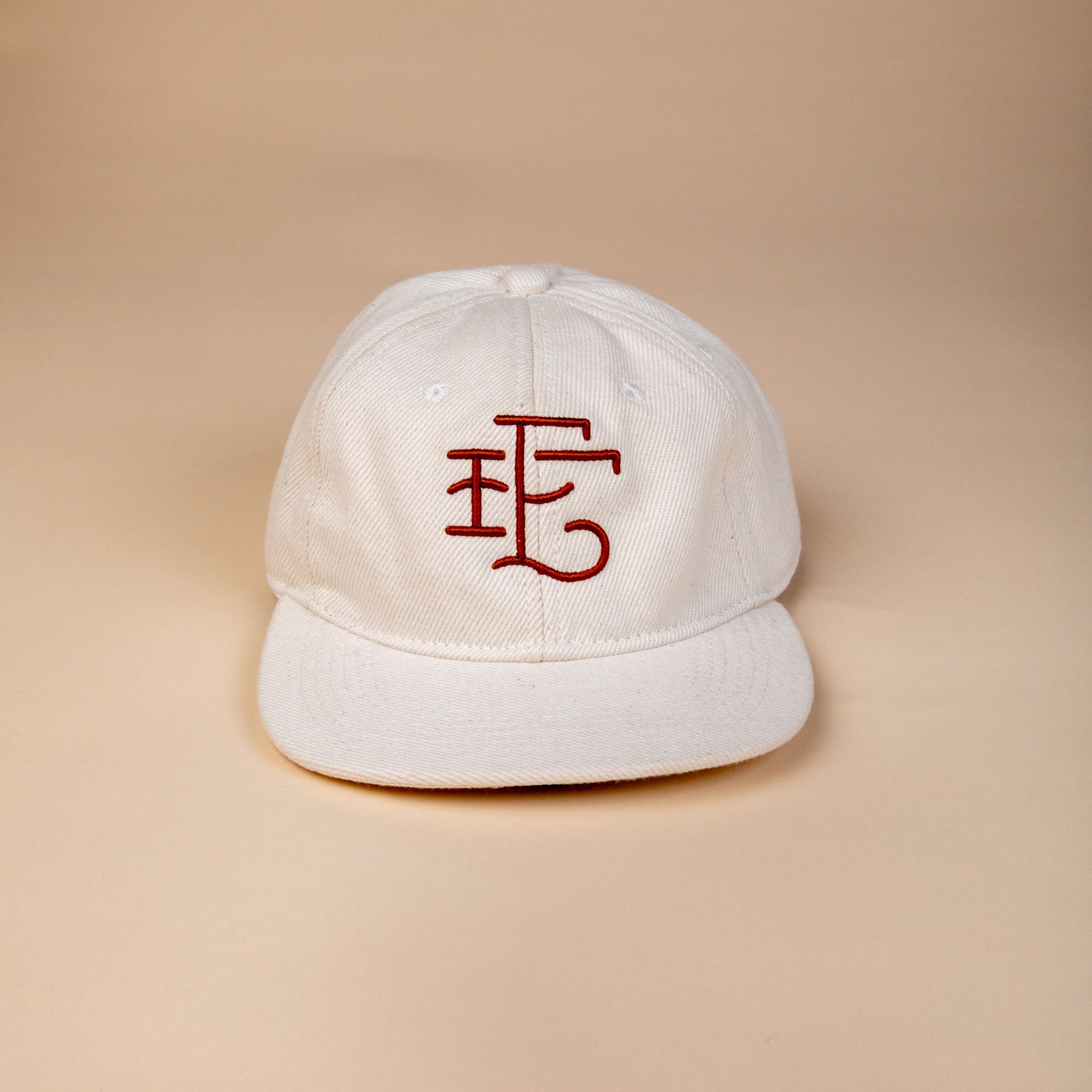 White denim baseball hat with a burnt terracotta stitching of East Fork's logo in a simple cursive - 'EF'.