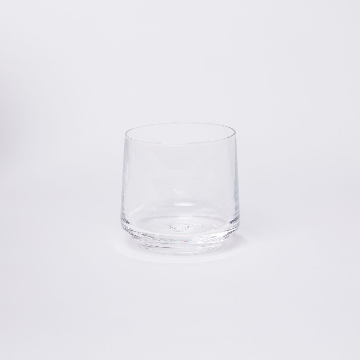 A clear glass tumbler that tapers towards the rim