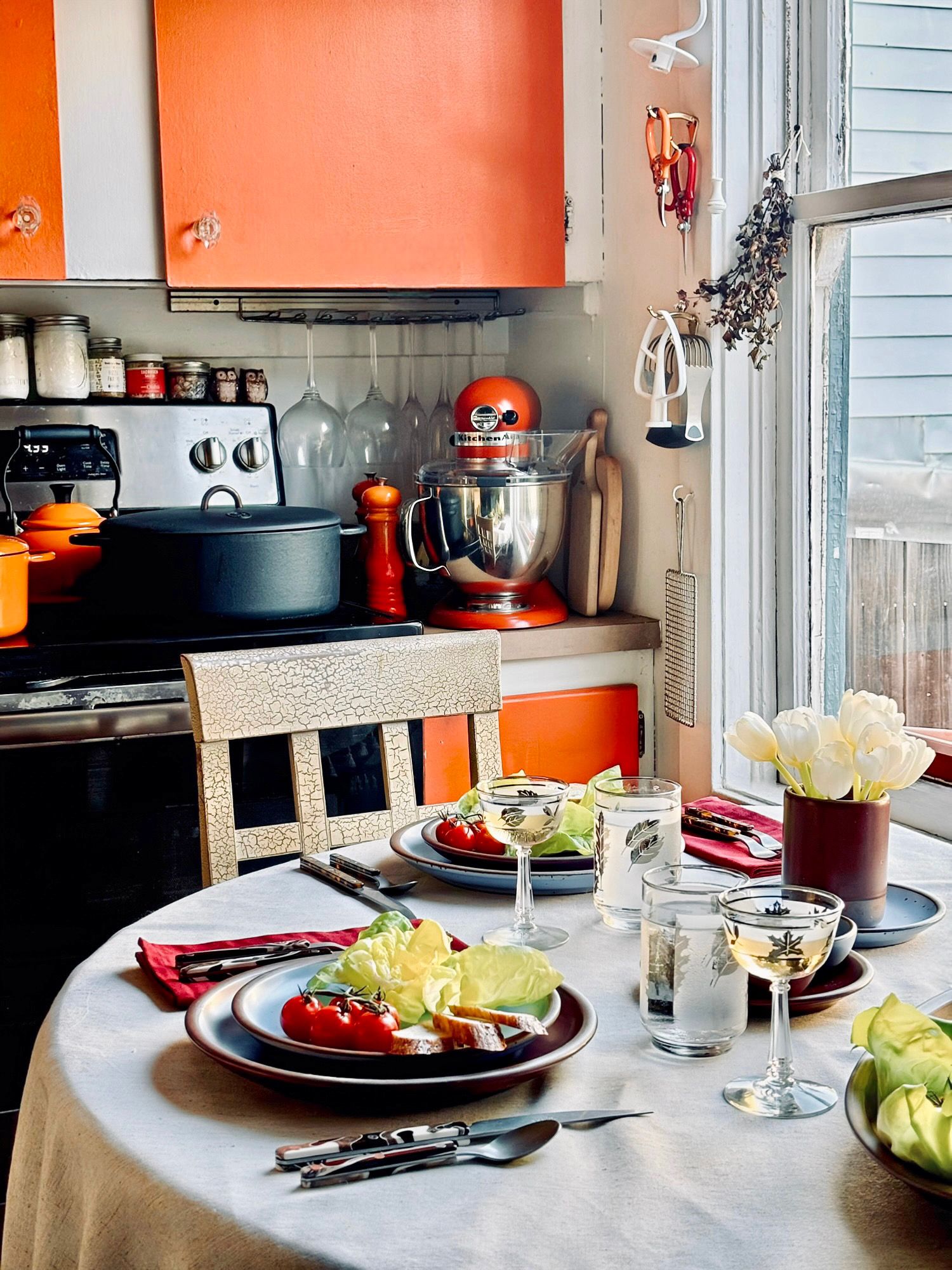 Bebe's dining table with place settings right next to her kitchen with orange cabinets.