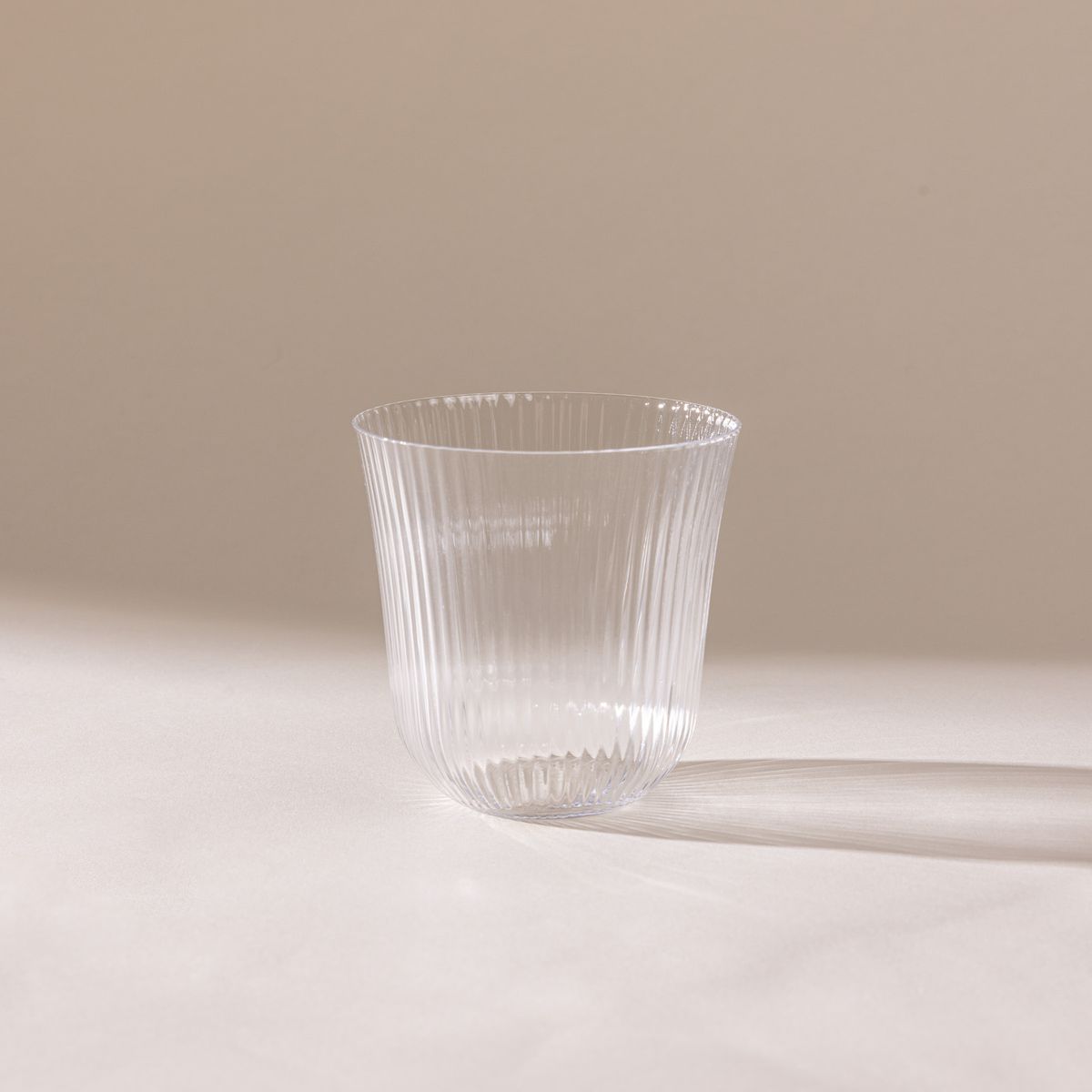 A delicate ribbed glass that has a rounded curve on the bottom and curves out on the top.