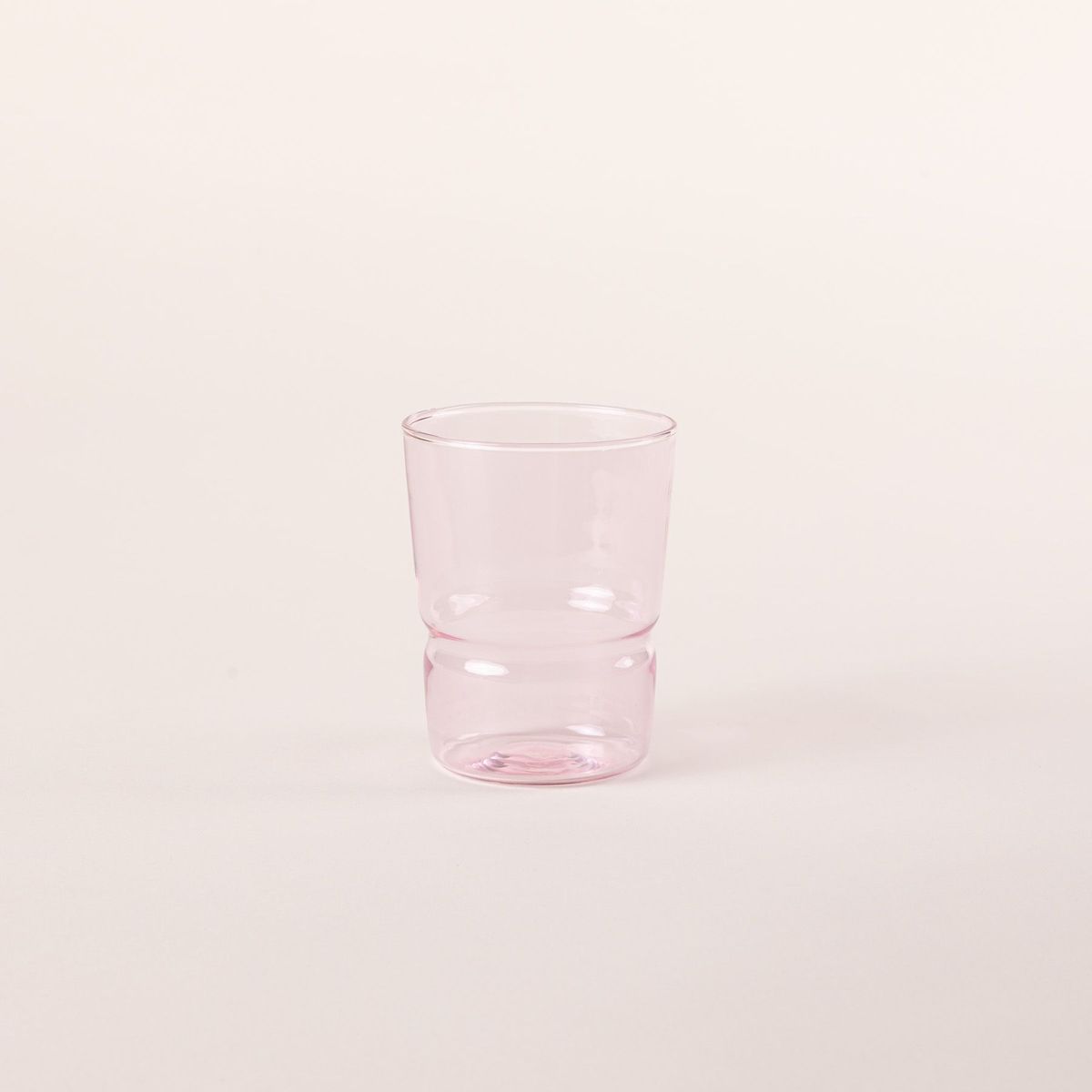 Tumbler glass that widens at the top in a soft pink color