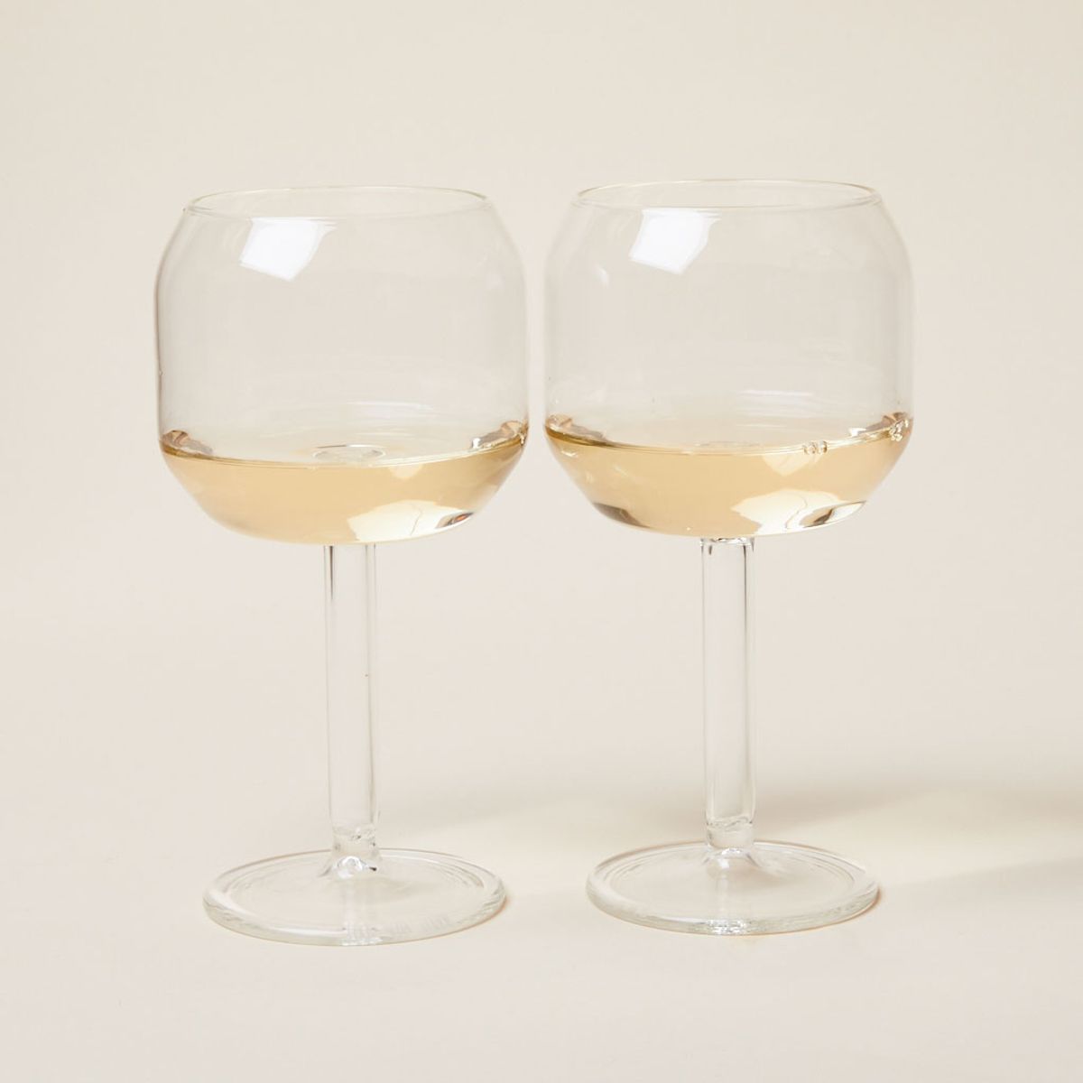 White wine partially fills two identical Velasca calices: stemmed wine glasses with large, tall bowls