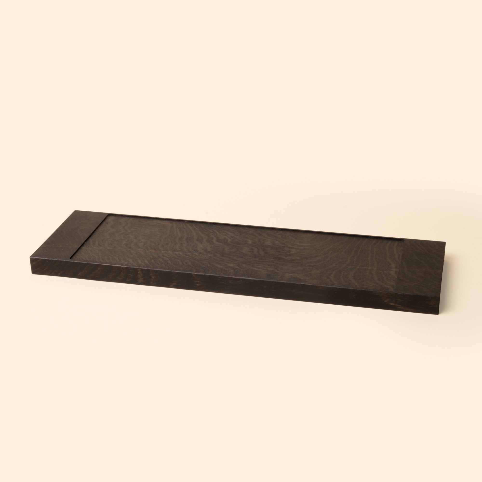 A narrow rectangle of ebonized oak wood with a vertical groove at either end