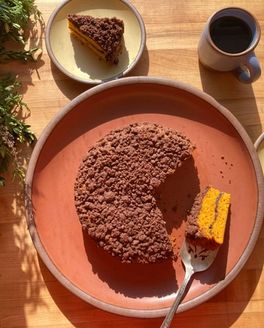A butternut coffee cake sitting on a terracotta color plate with slices plated on small cake plates in a butter color.
