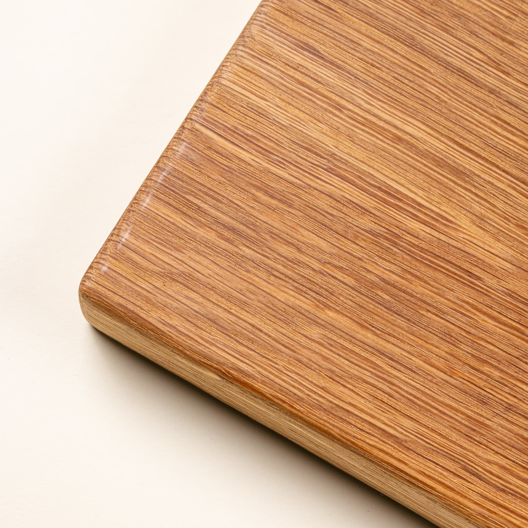 A close up of a smooth corner of a rectangular white oak cutting board