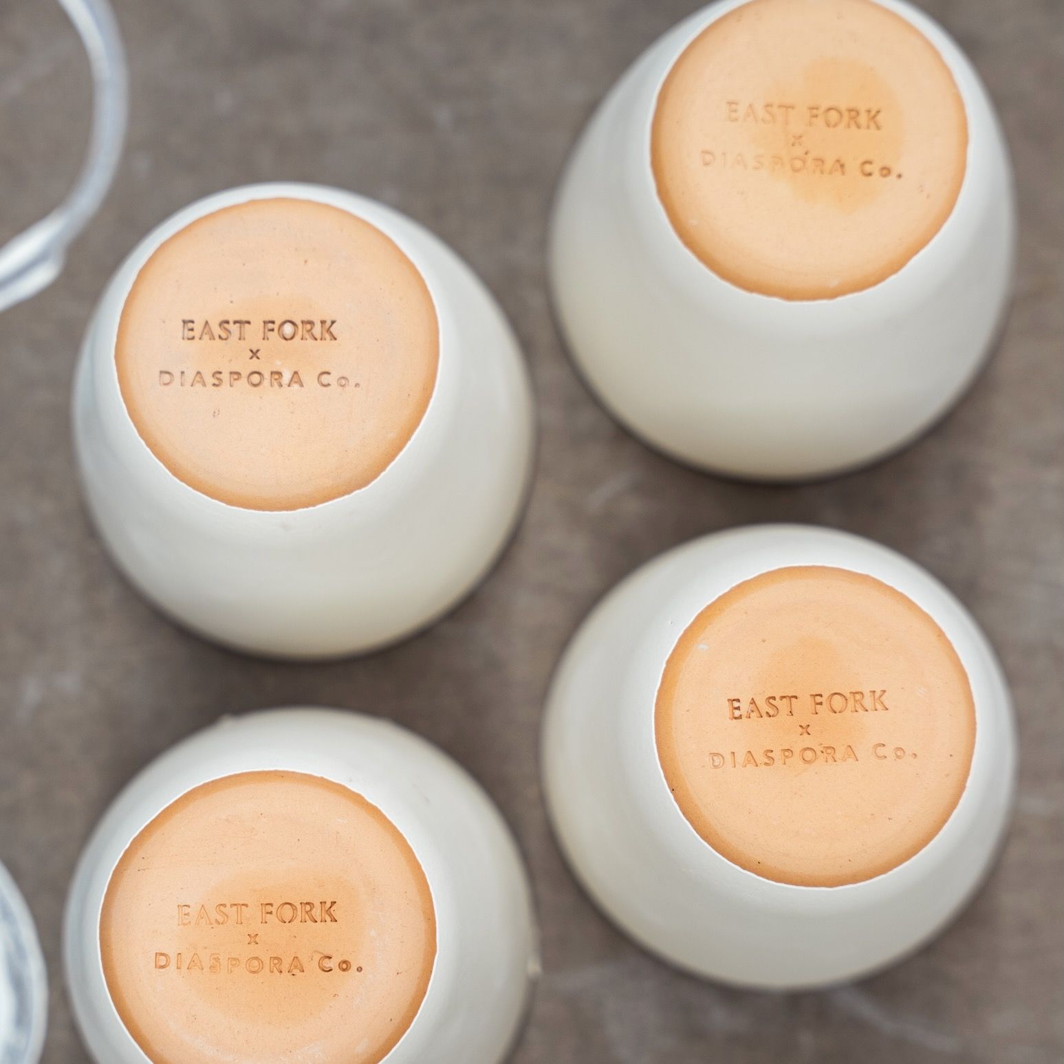 Four upside-down ceramic cups stamped on the base with “East Fork x Diaspora Co.” in collaboration branding.