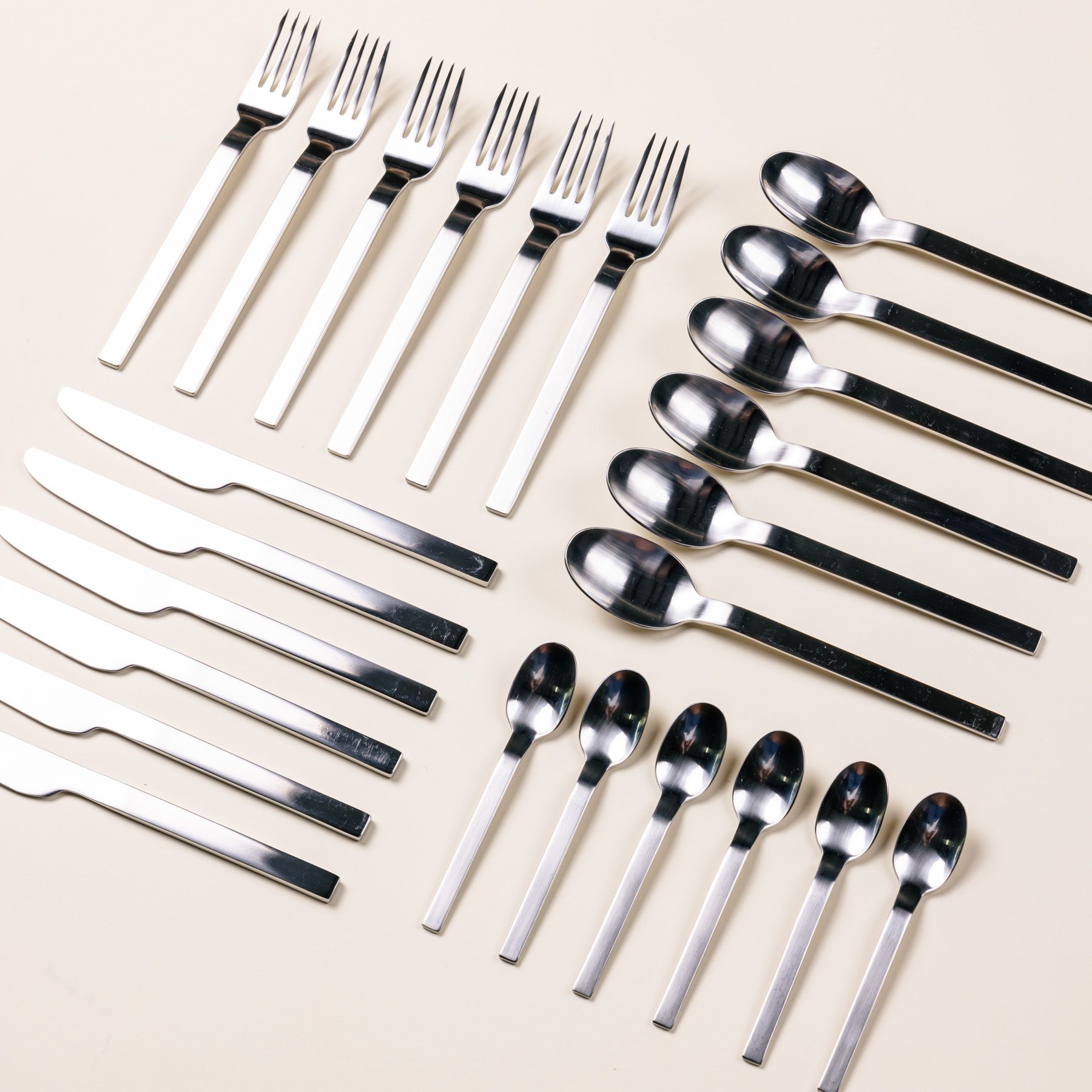 Artful geometric arrangement of a set of 6 steel teaspoons, spoons, knives, and forks