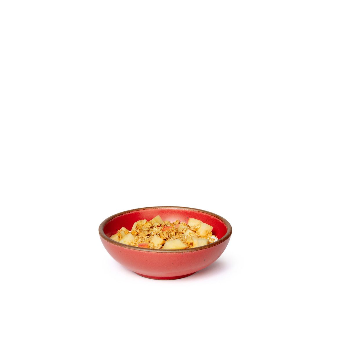 Food in a small shallow ceramic bowl in a bold red color featuring iron speckles and an unglazed rim