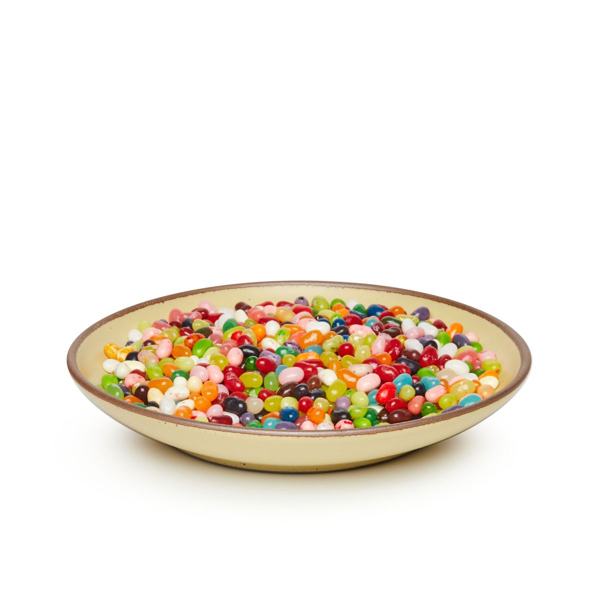 Jelly beans on a large ceramic plate with a curved bowl edge in a light butter yellow color featuring iron speckles and an unglazed rim