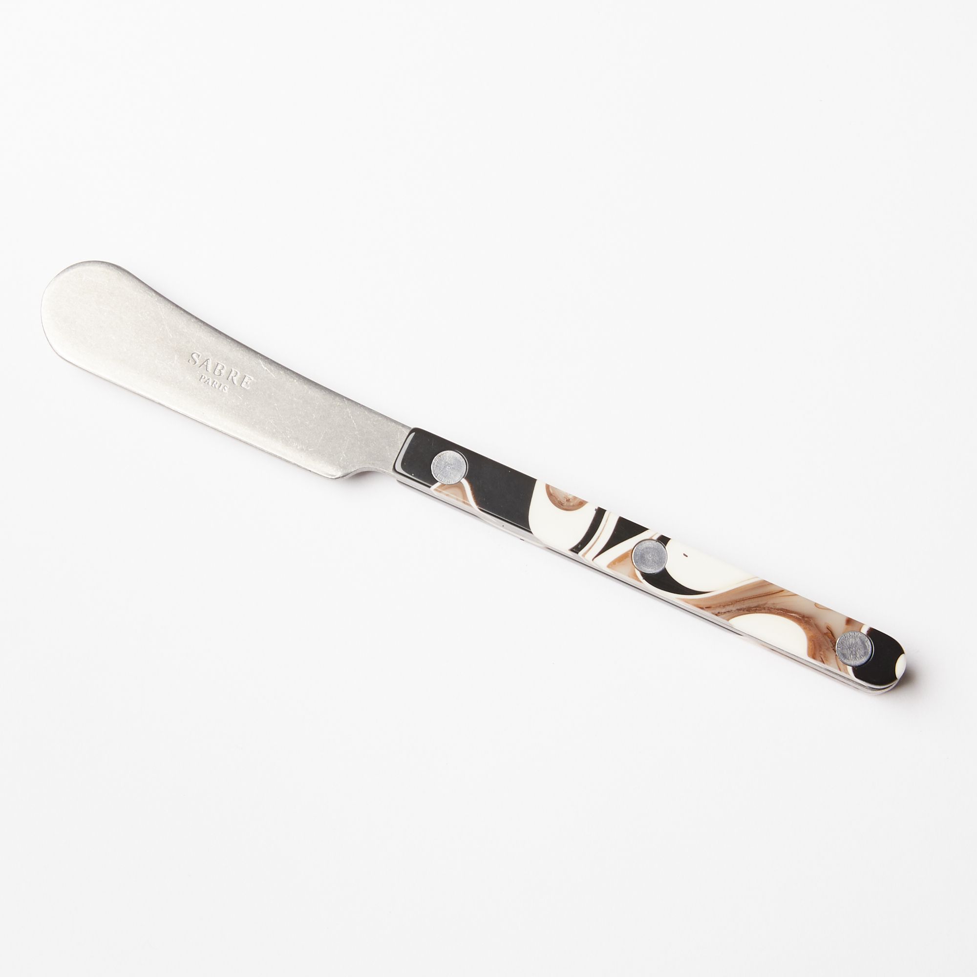 A butter knife with a stainless steel blade and an acrylic black, white, and brown handle