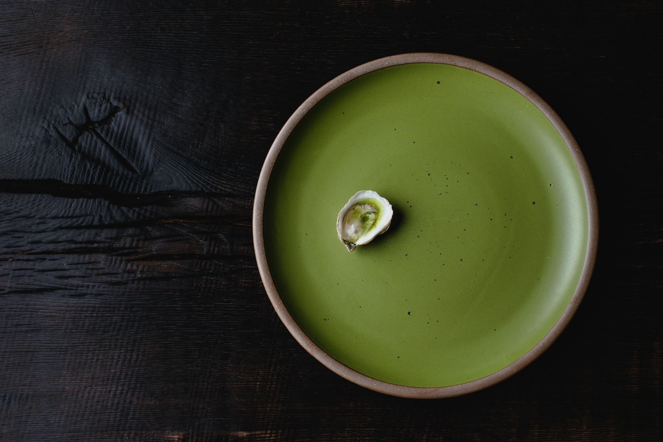 A single oyster on an East Fork platter in Fiddlehead green.