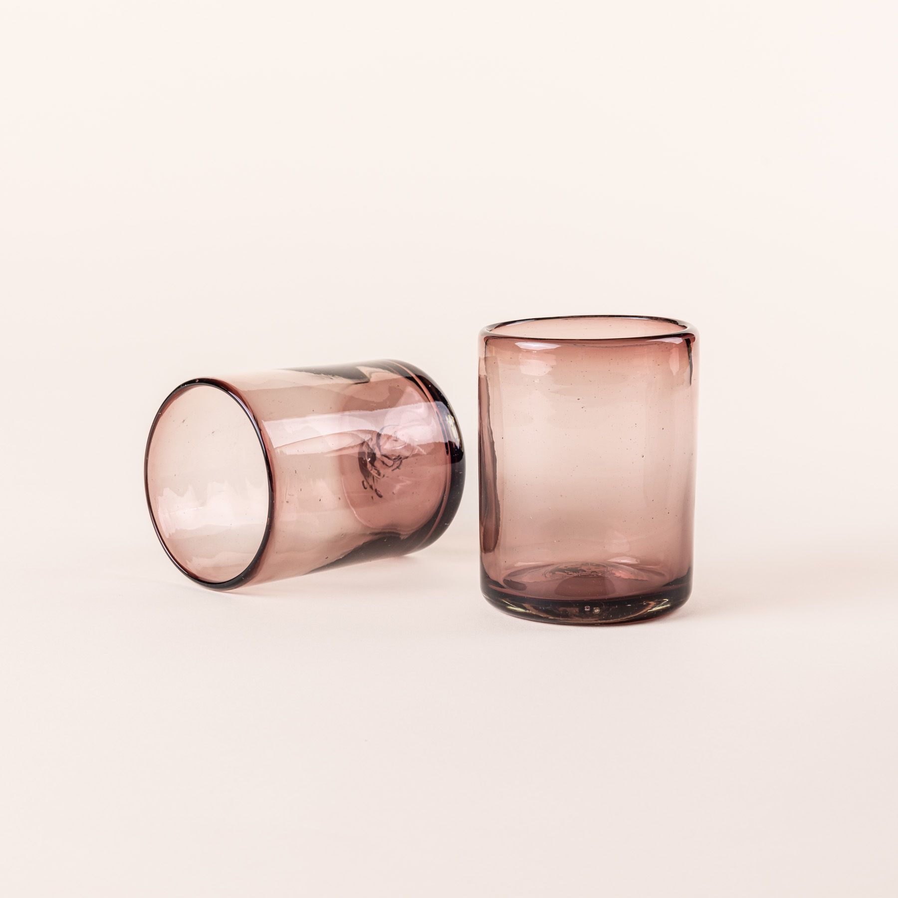 A light plum short drinking glass sitting up and one on its side