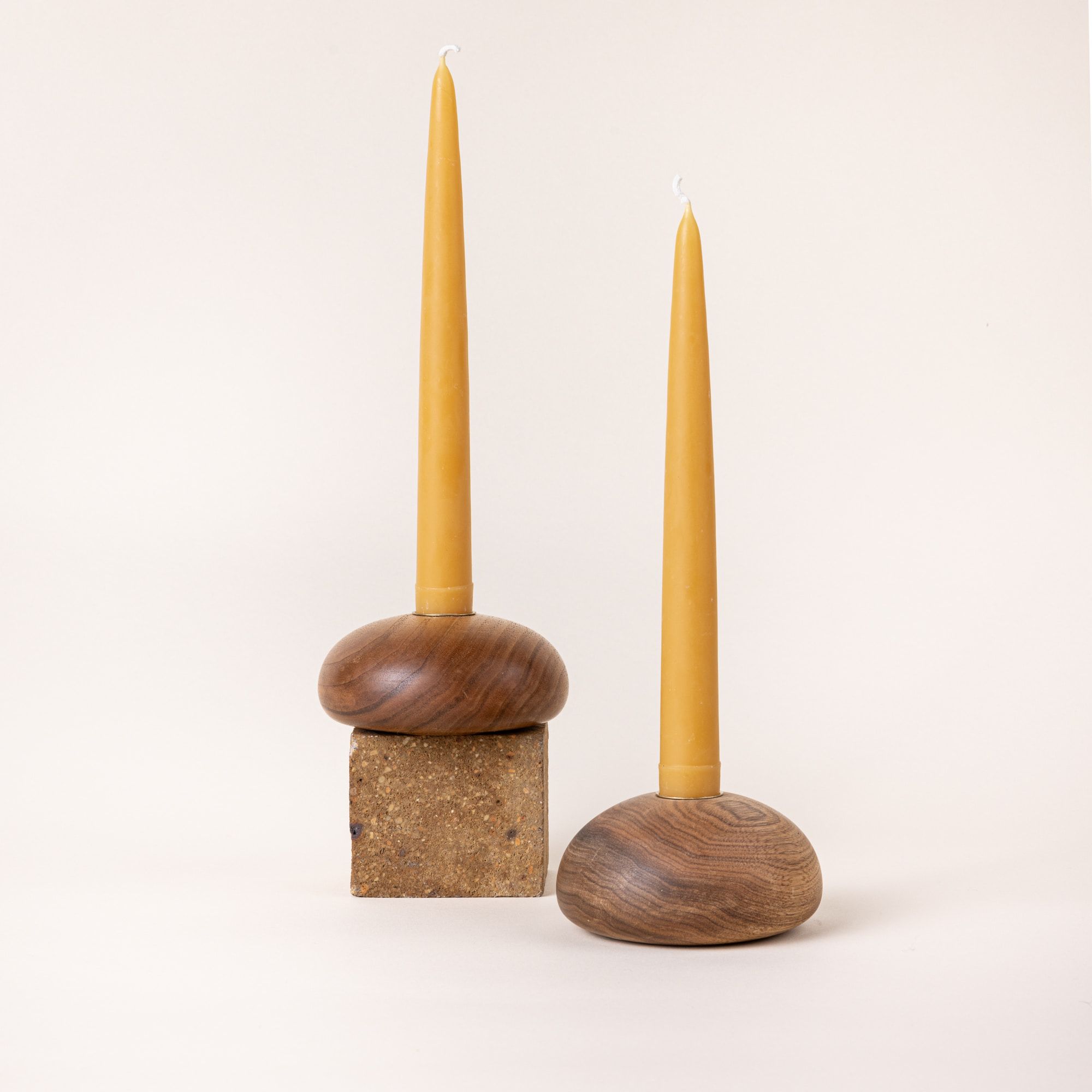 A pair of yellow beeswax taper candles sitting in round wooden candle holders