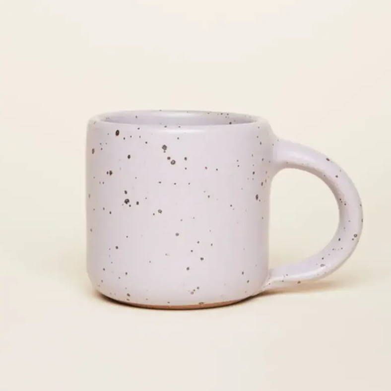 A medium sized ceramic mug with handle in a light pastel purple featuring iron speckles