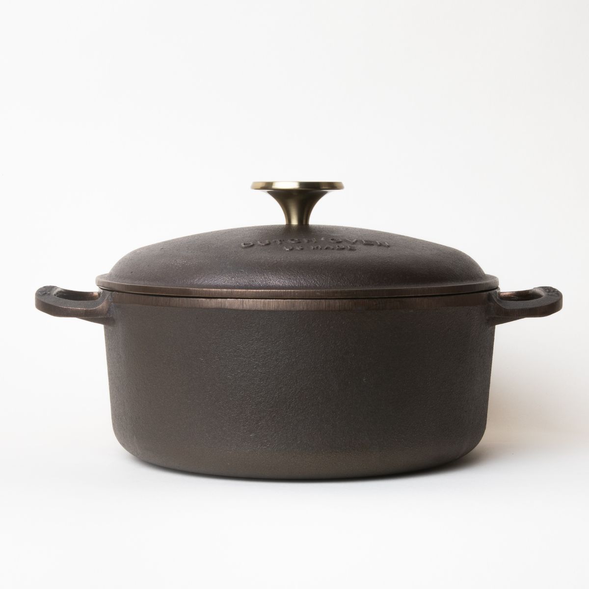 Cast iron dutch oven with a handle on each side and cast iron lid with a gold metal knob