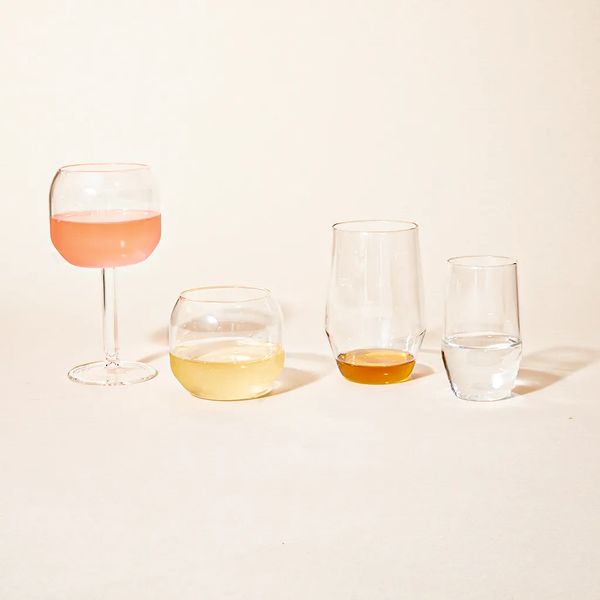 An assortment of R+D glassware, filled with light white wine, orange wine and water.