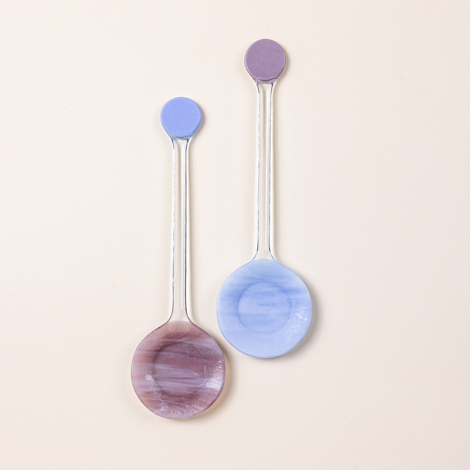 Two modern glass colorblocked serving spoons in periwinkle and plum colors.