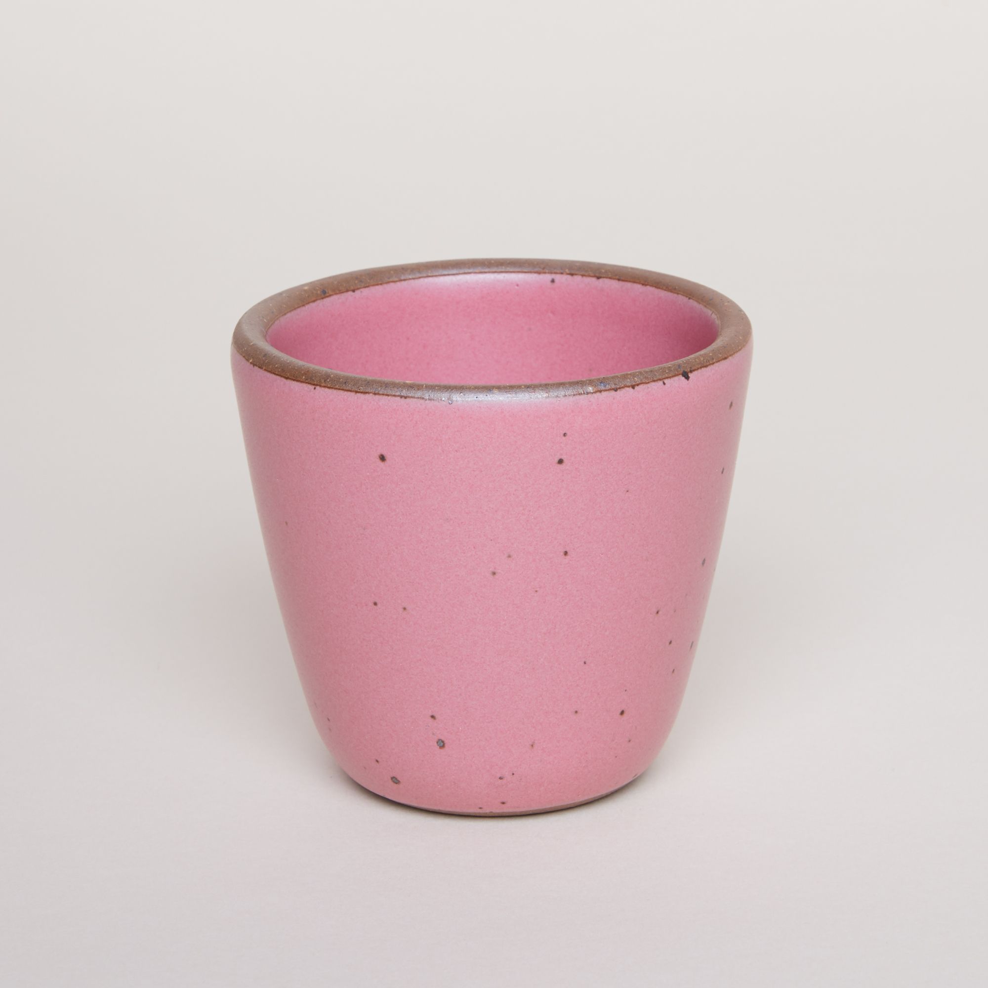 A bright pink handleless mug