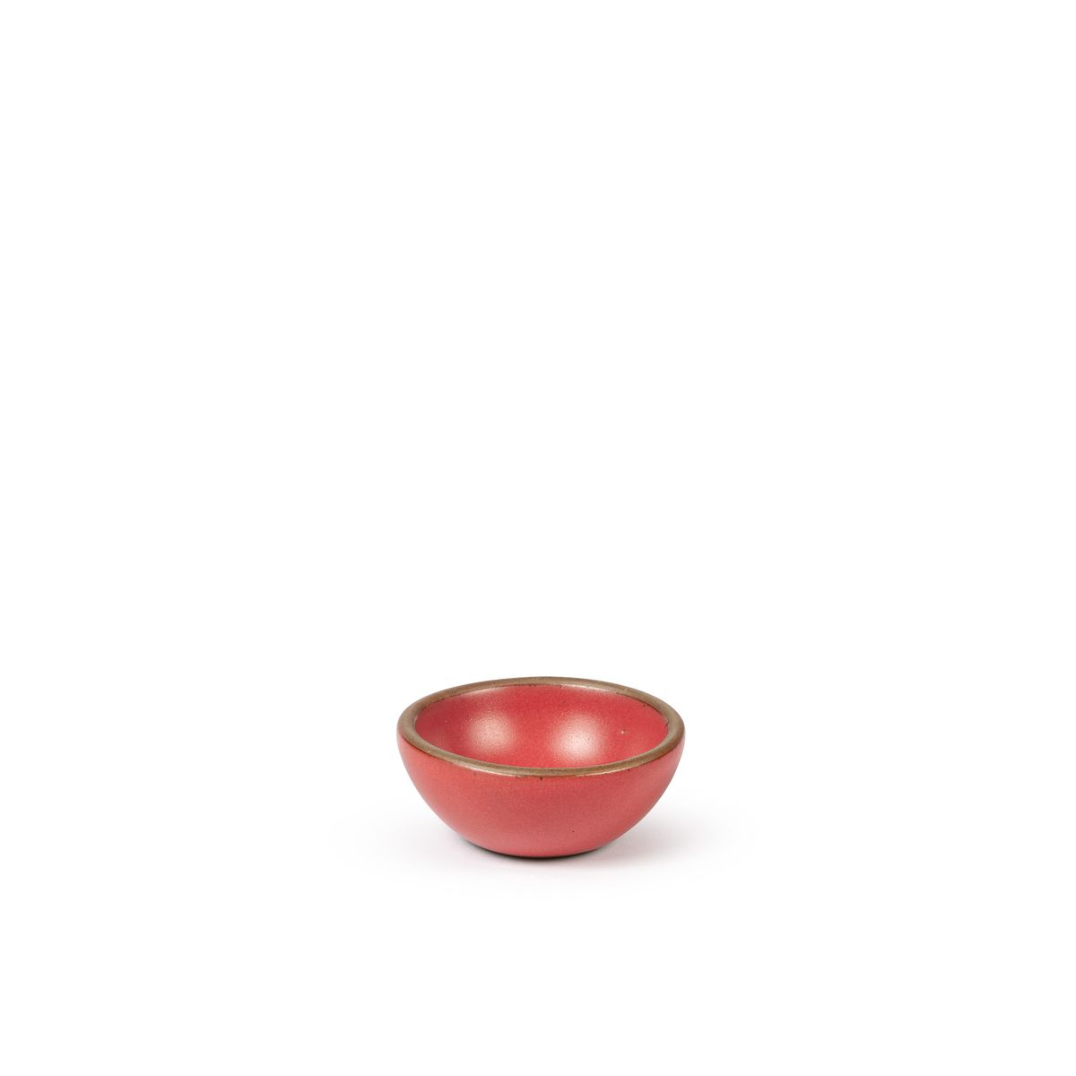 A tiny rounded ceramic bowl in a bold red color featuring iron speckles and an unglazed rim