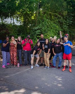 People from Operation Gateway are lined up and smiling sharing peace signs outside.