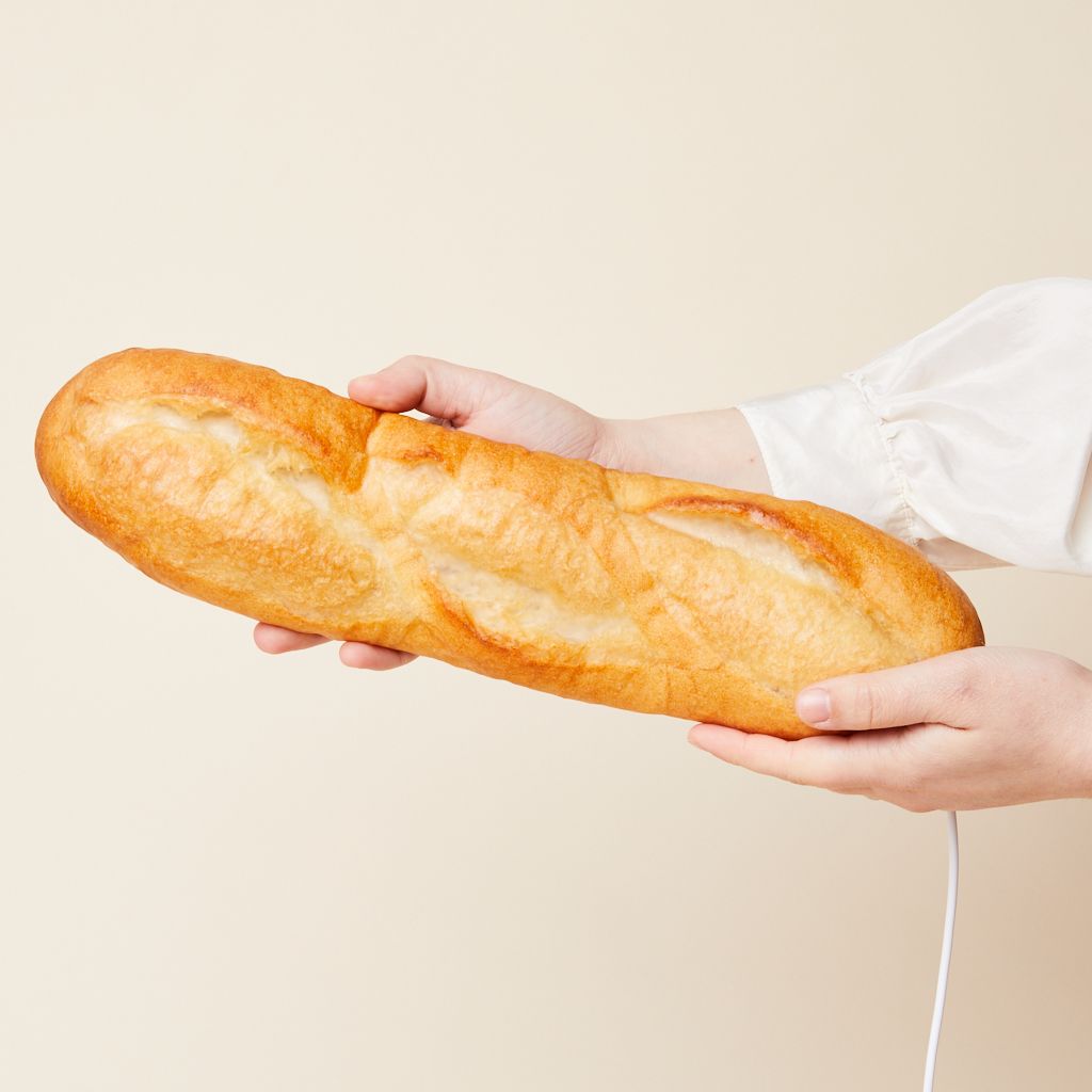 Hands holding a lamp that looks like a batard bread.