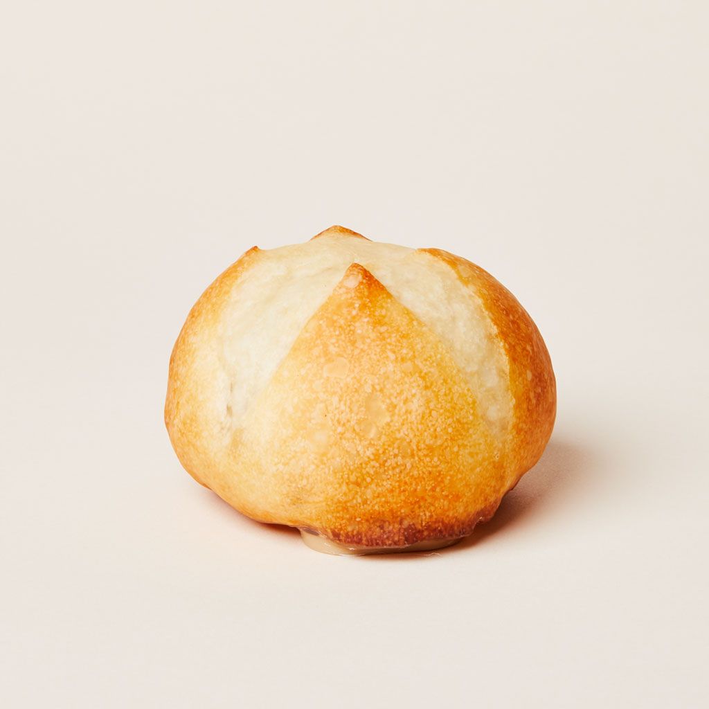 A round ball-like object in shades of light brown, darker near the base and lighter at the top, with the size and texture of a dinner roll