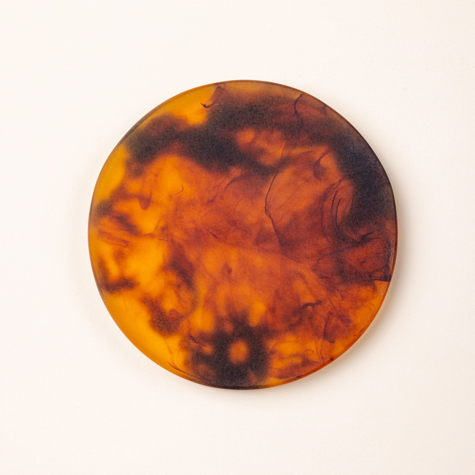 A close up of 1 circular tortoiseshell coasters