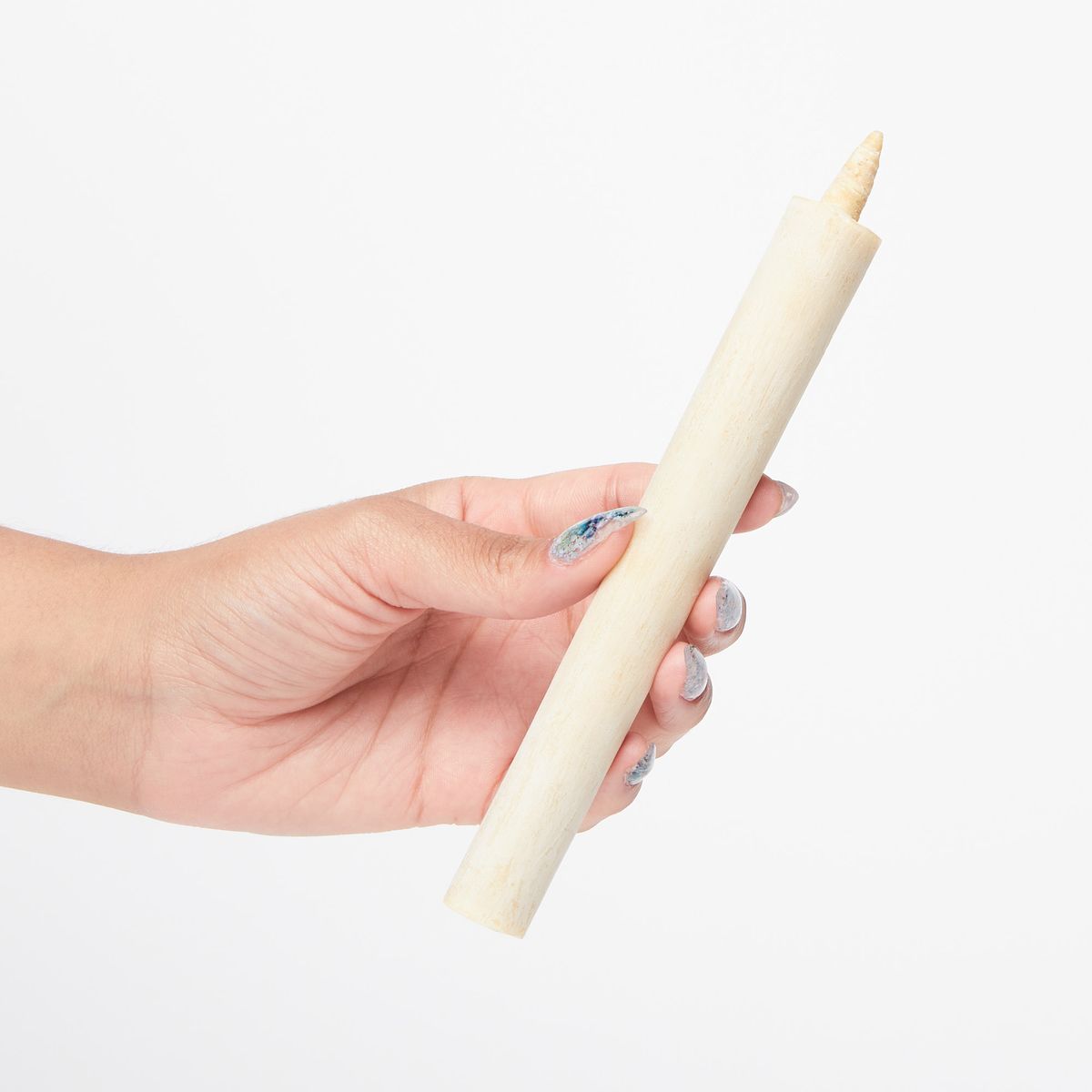 Hand holding an unlit cream colored taper candle at a slight angle
