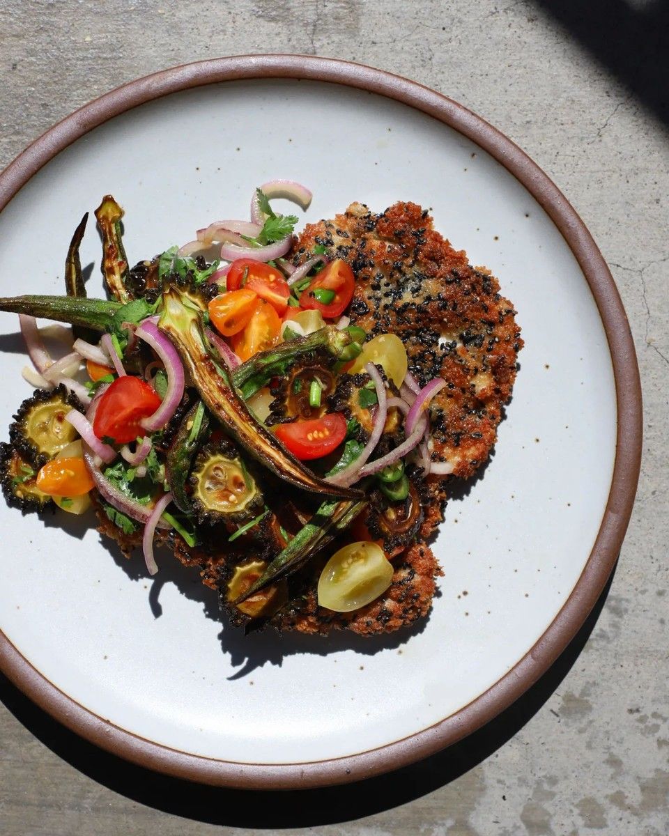 An artful colorful entree is plated on a ceramic plate in a white color.