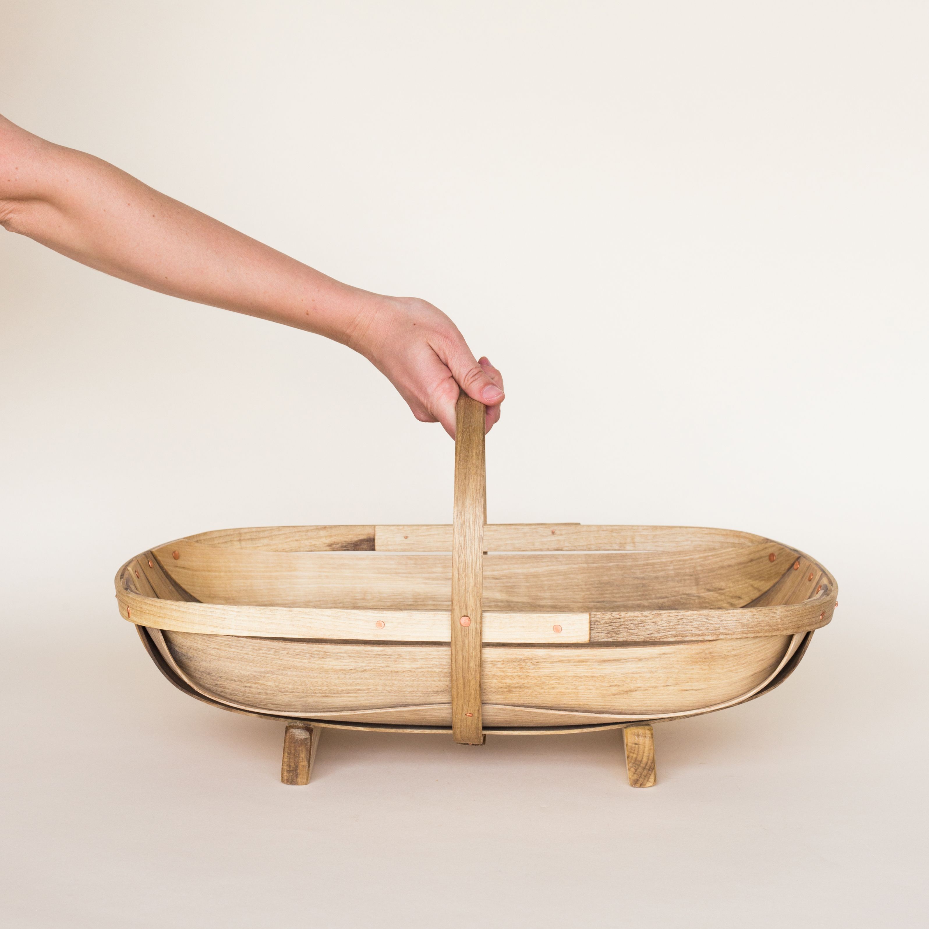 A hand reaches for a large myrtlewood trug for harvesting