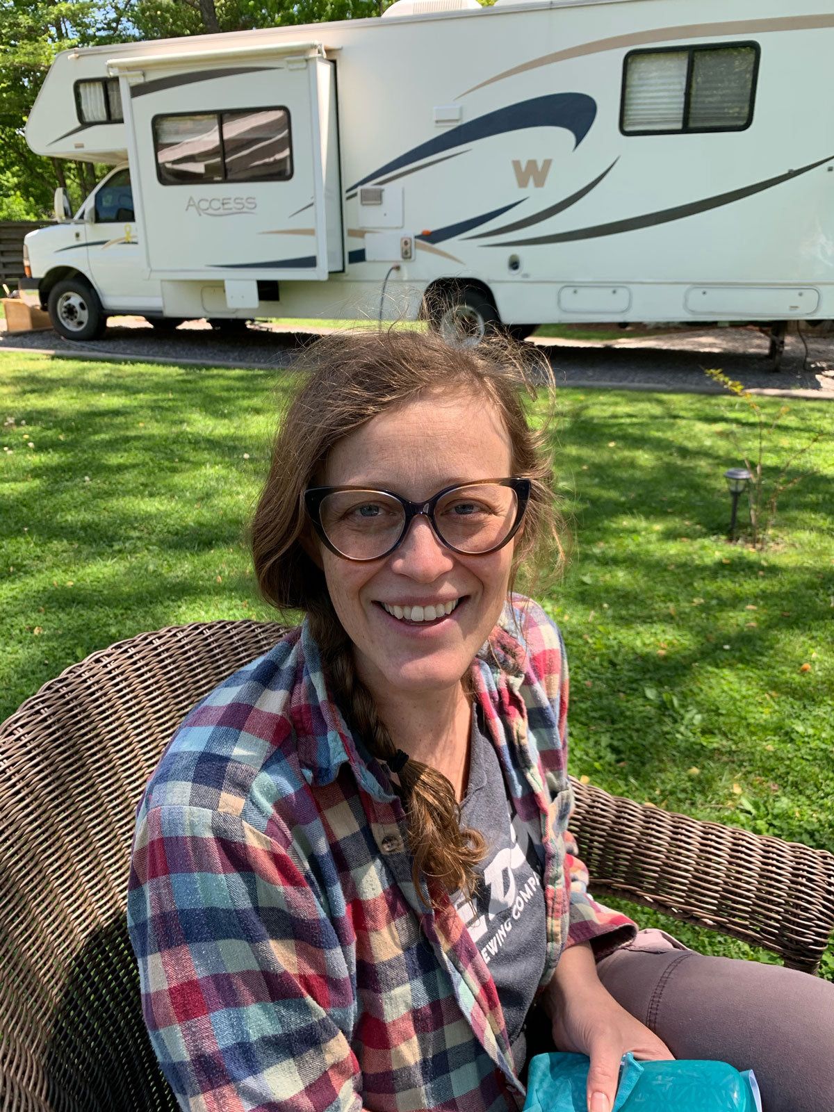 Outside, Lisa is wearing a flannel and sitting in a chair turned and smiling at the camera.