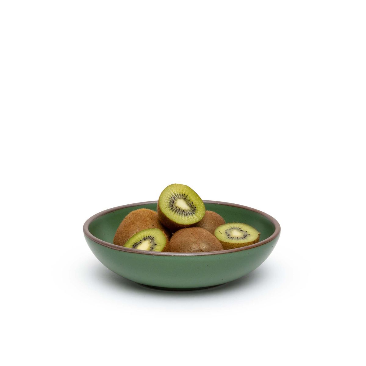 A dinner-sized shallow ceramic bowl in a deep, verdant green color featuring iron speckles and an unglazed rim, filled with sliced kiwis