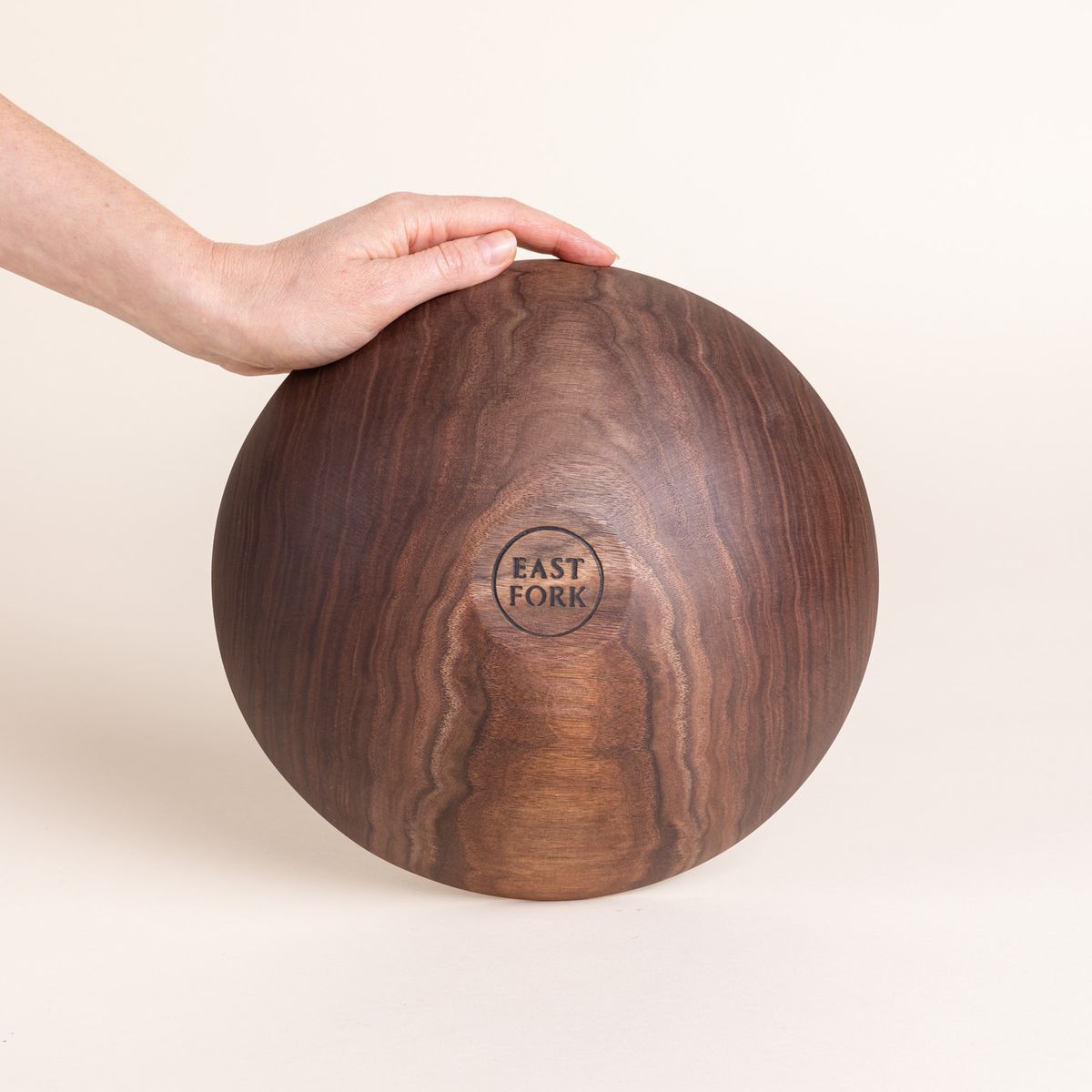 The bottom of a medium walnut wood bowl with a stamp that reads "East Fork"