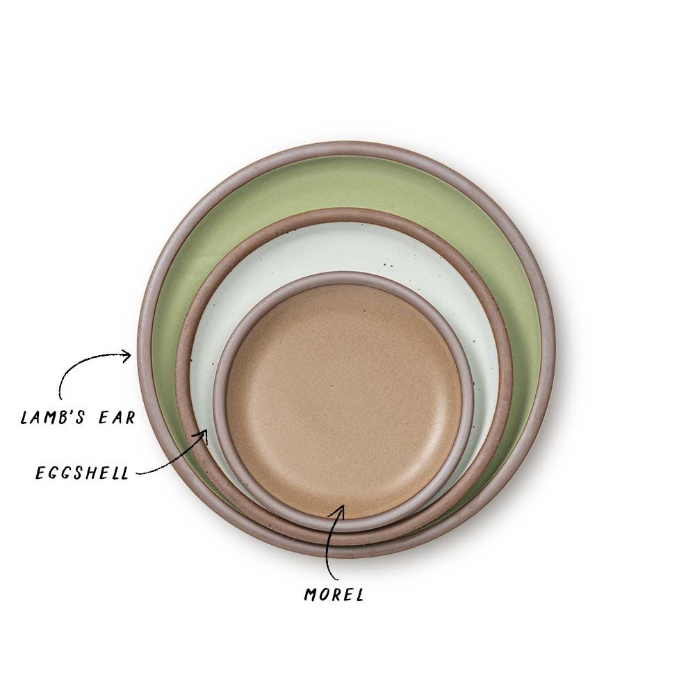 A stack of ceramic plates in a calming sage green, cool white, and muted tan colors.