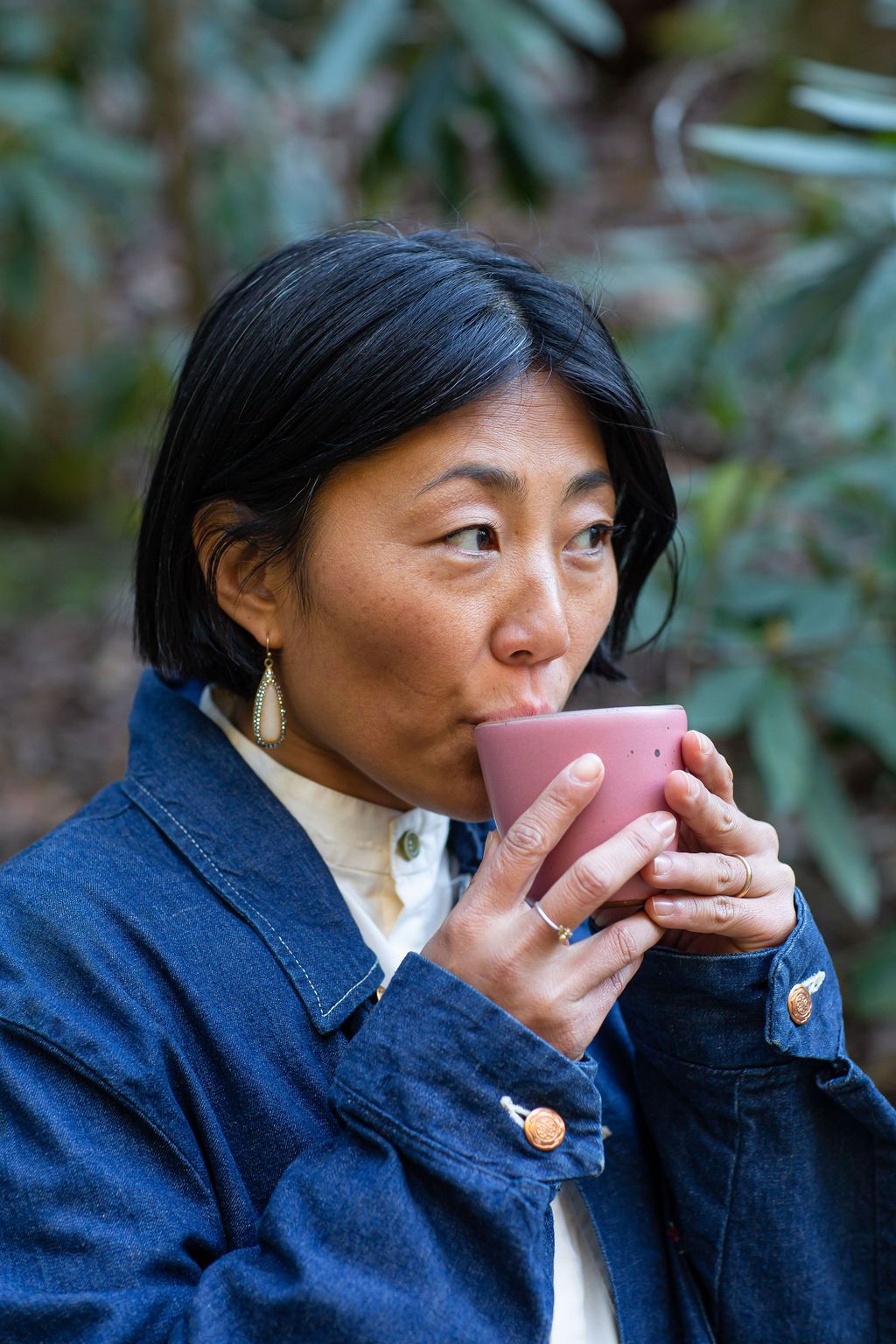 A woman sips from a hot pink East Fork Pottery Chai Kulhad in a forested setting