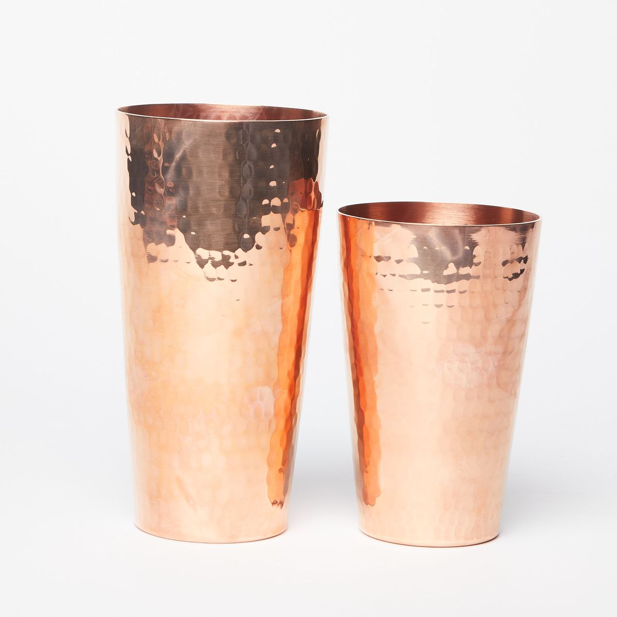Two hammered copper cups, larger one of the left and smaller on the right