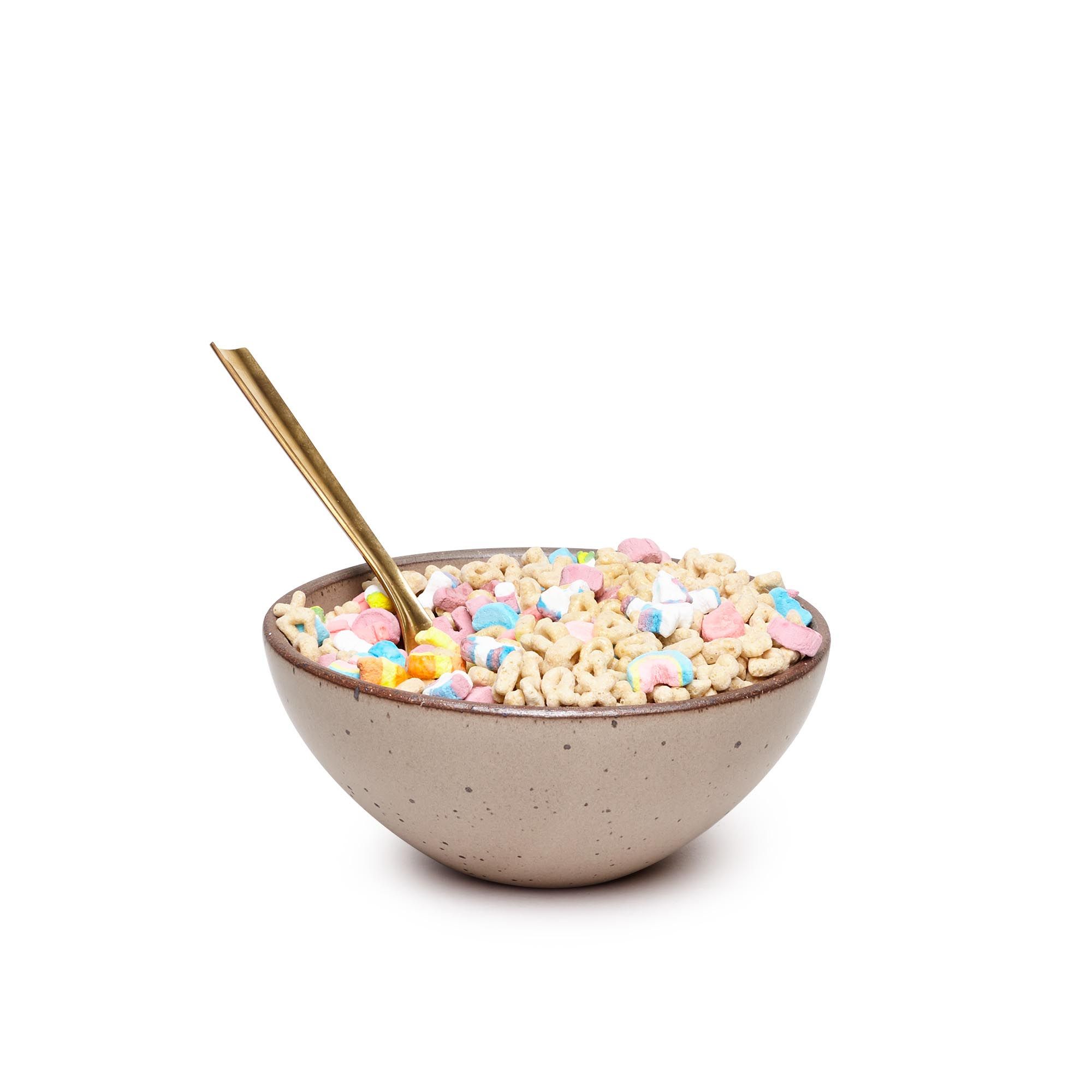 A medium rounded ceramic bowl in a warm pale brown color featuring iron speckles and an unglazed rim, filled with cereal and brass spoon
