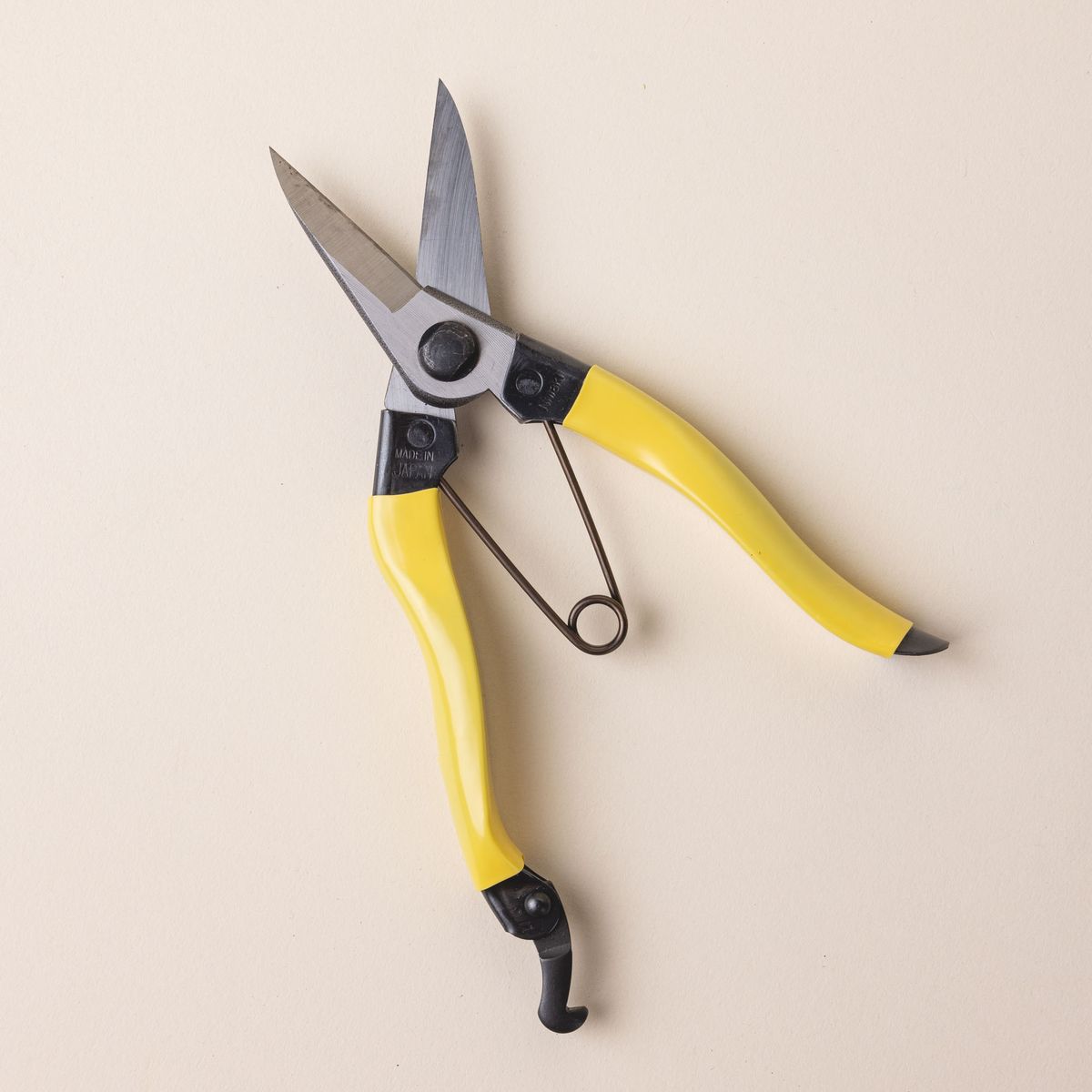 A pair of garden snips with a yellow handle and wide short blades