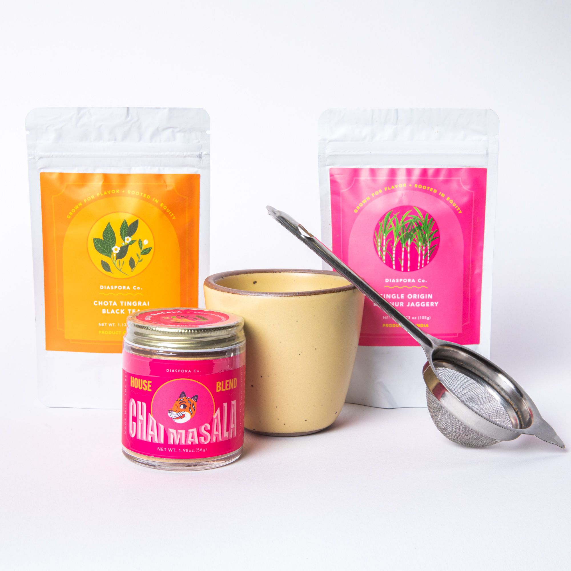 A chai bundle featuring a soft butter yellow kulhad, a tea strainer, a pink jar of chai masala, and 2 packages of jaggery and black tea