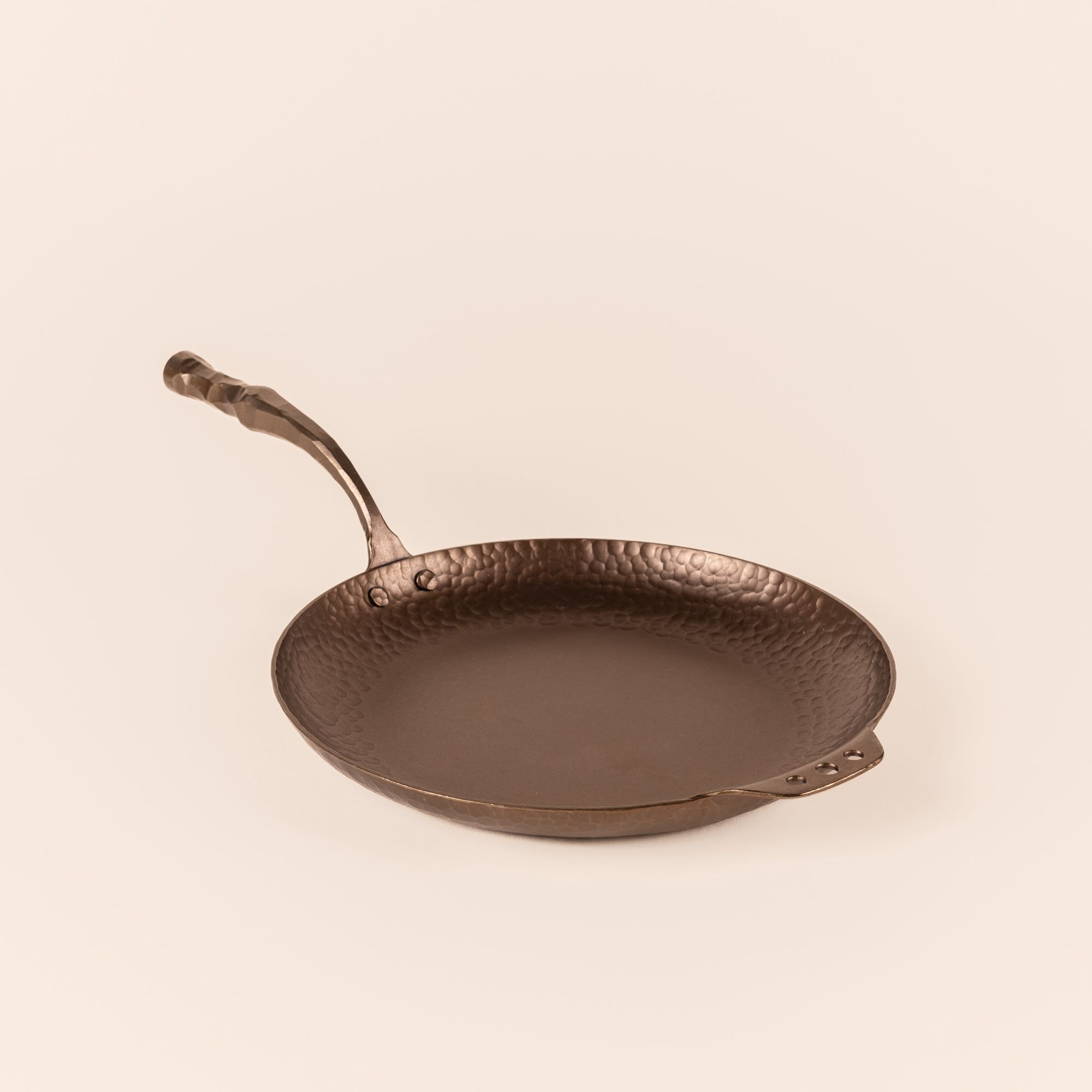 A carbon steel farmhouse skillet with a hammered texture and hand forged design