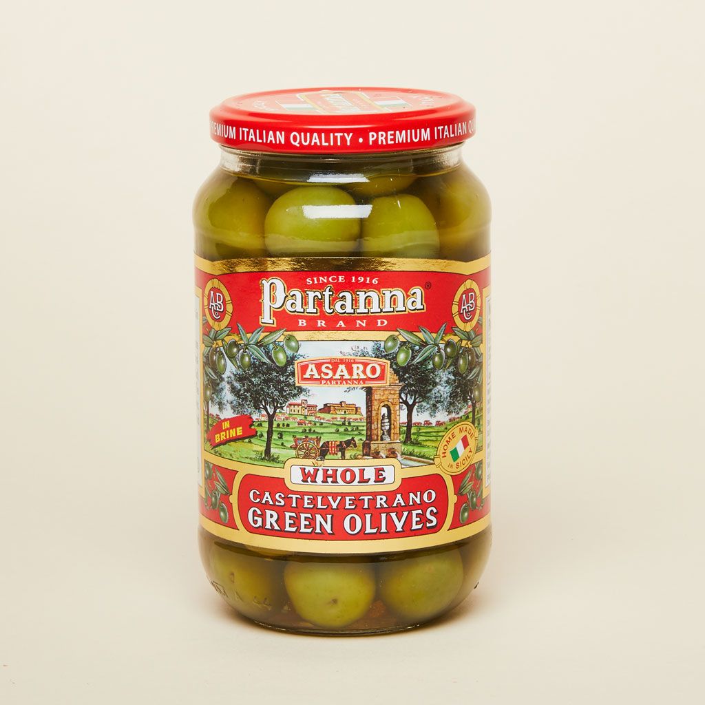 A glass jar with a red lid filled with green olives