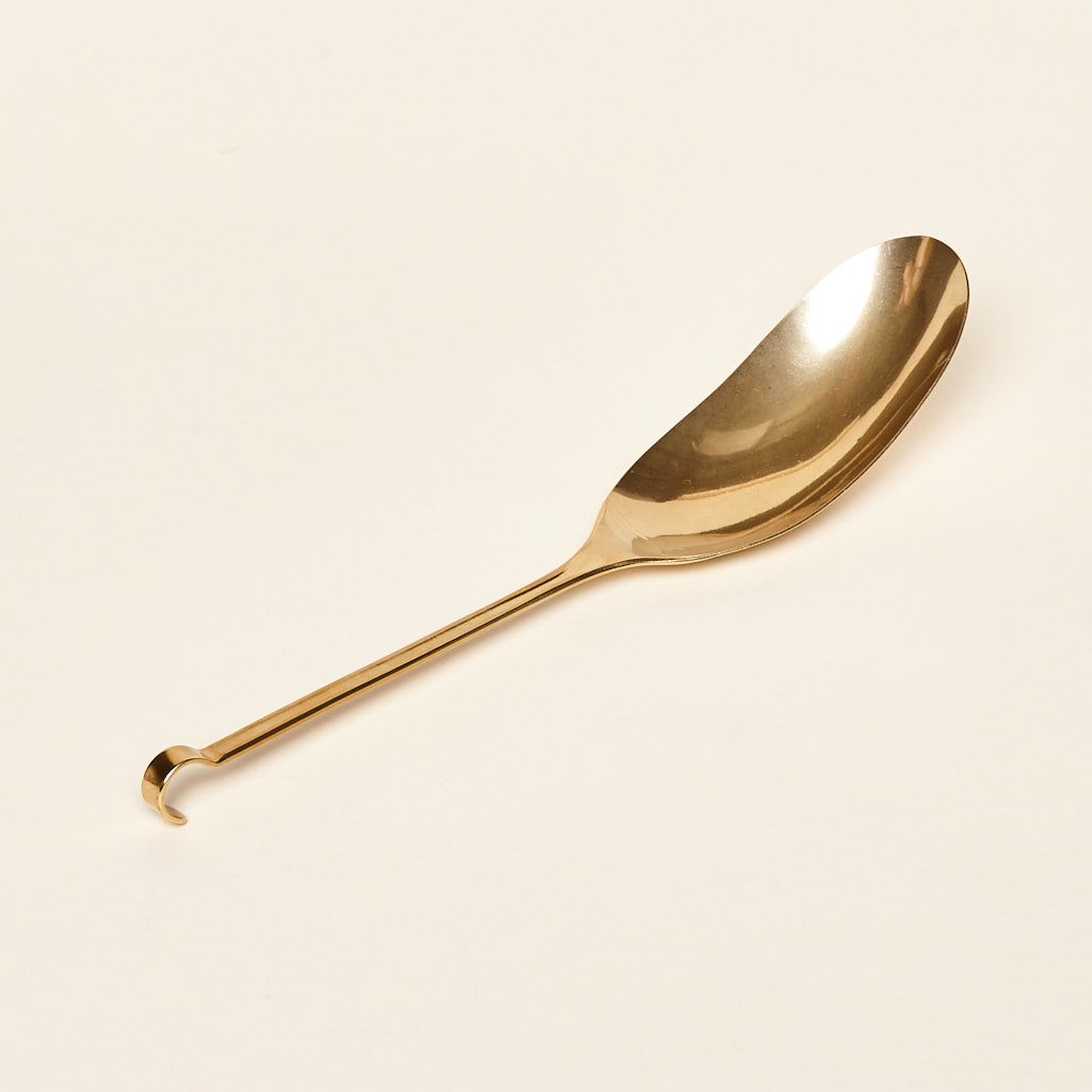 A brass spoon with an oversized long, narrow bowl