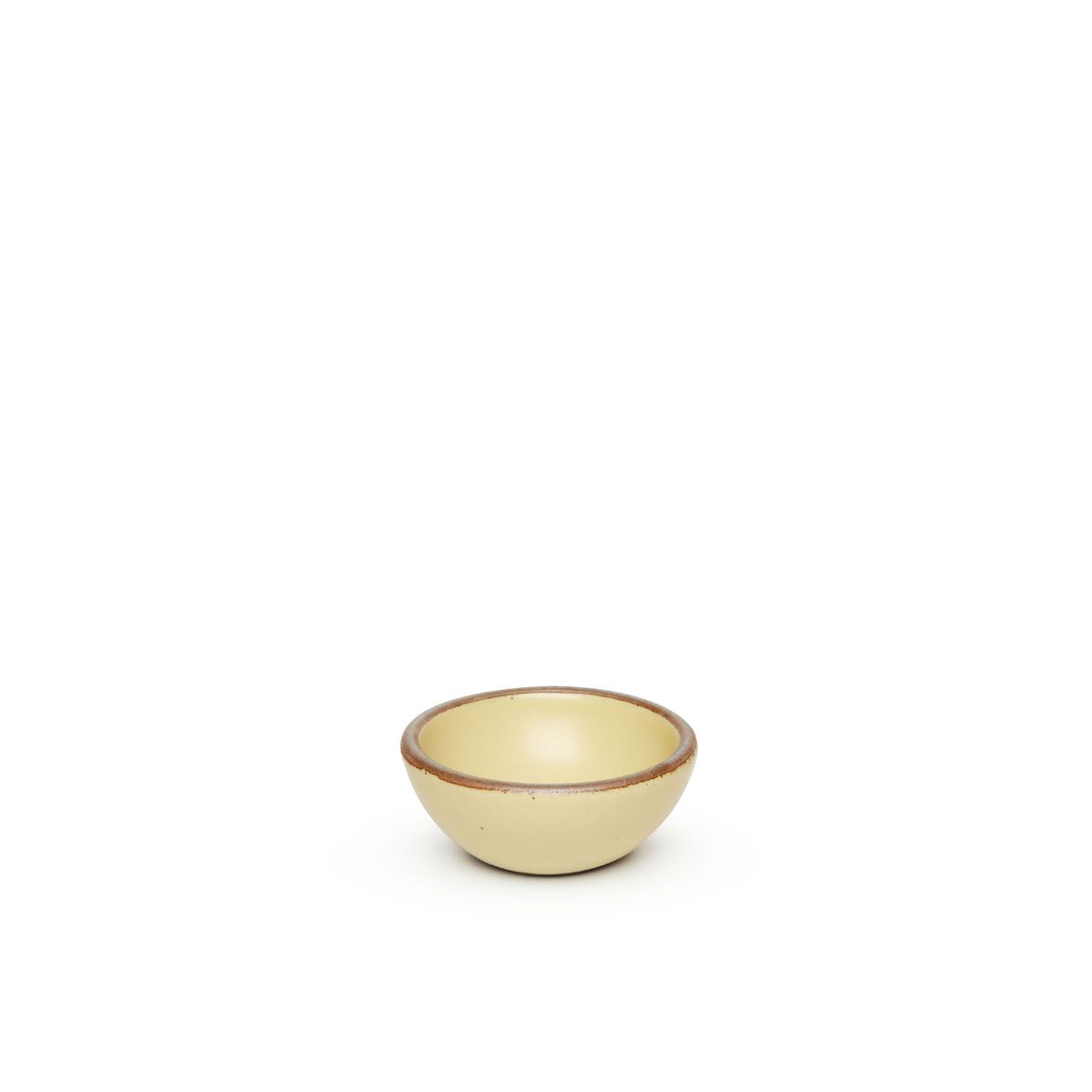 A tiny rounded ceramic bowl in a light butter yellow color featuring iron speckles and an unglazed rim