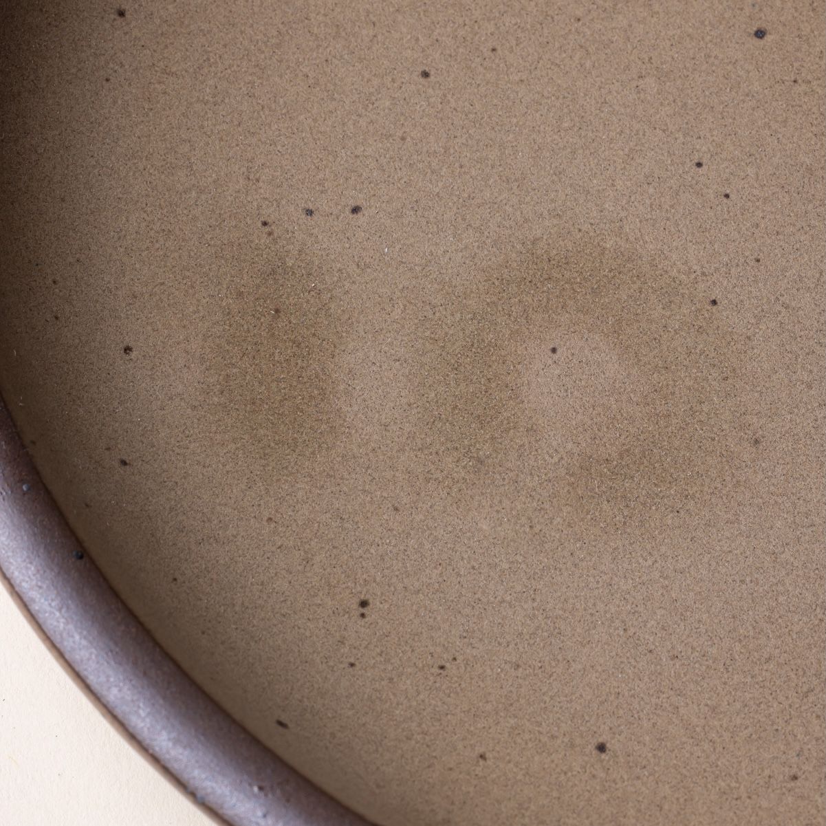 A closeup of a ceramic plate with water marks inside the glaze.