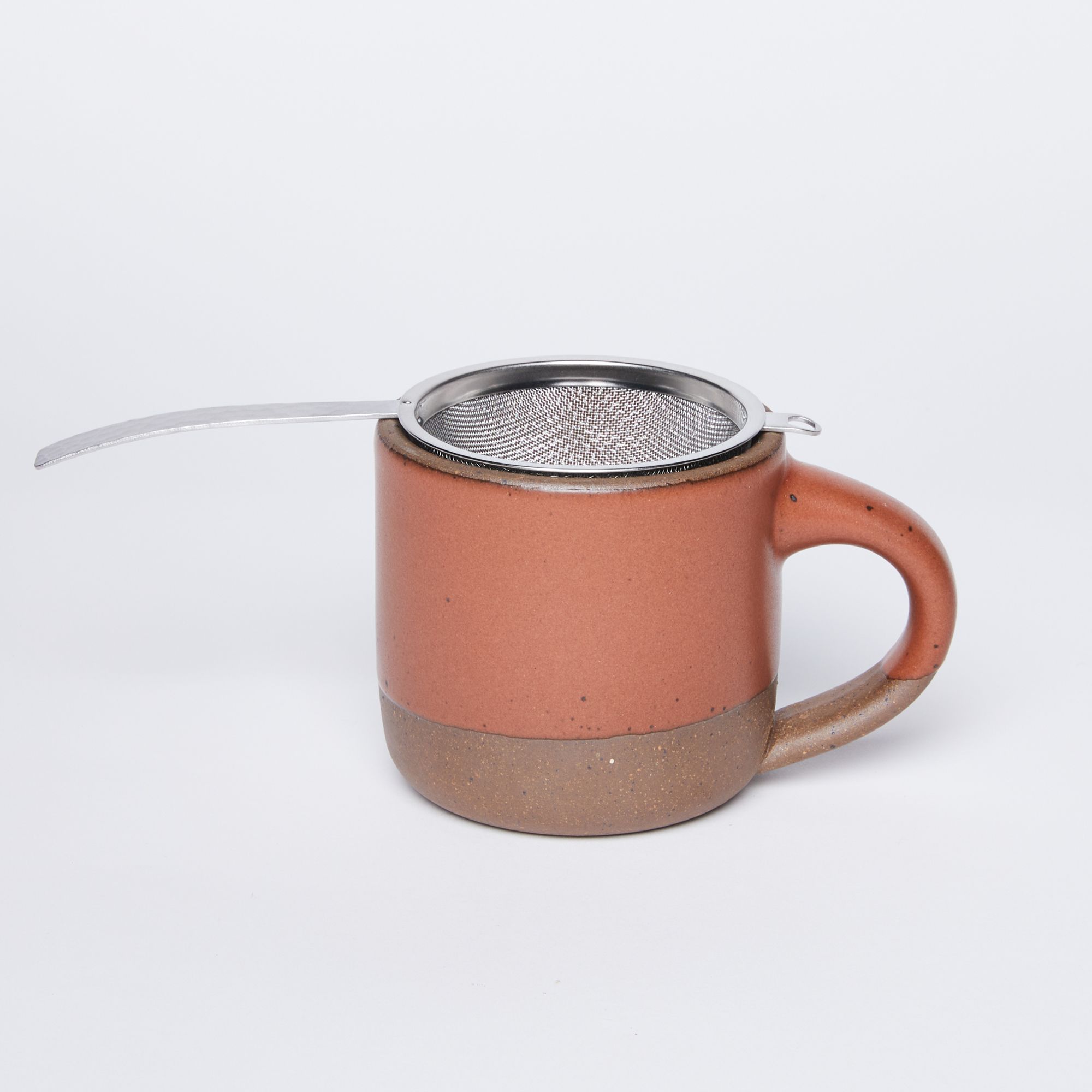 Stainless steel half dome strainer with steel handle on top of opening of The Small Mug in Amaro