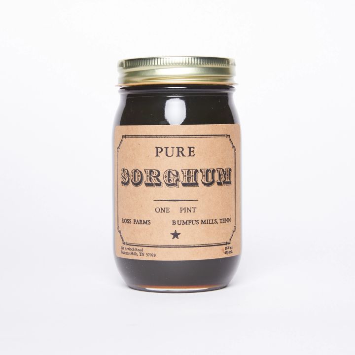 Clear glass pint jar full of a deep brown liquid with a natural color label that reads "Pure Sorghum"