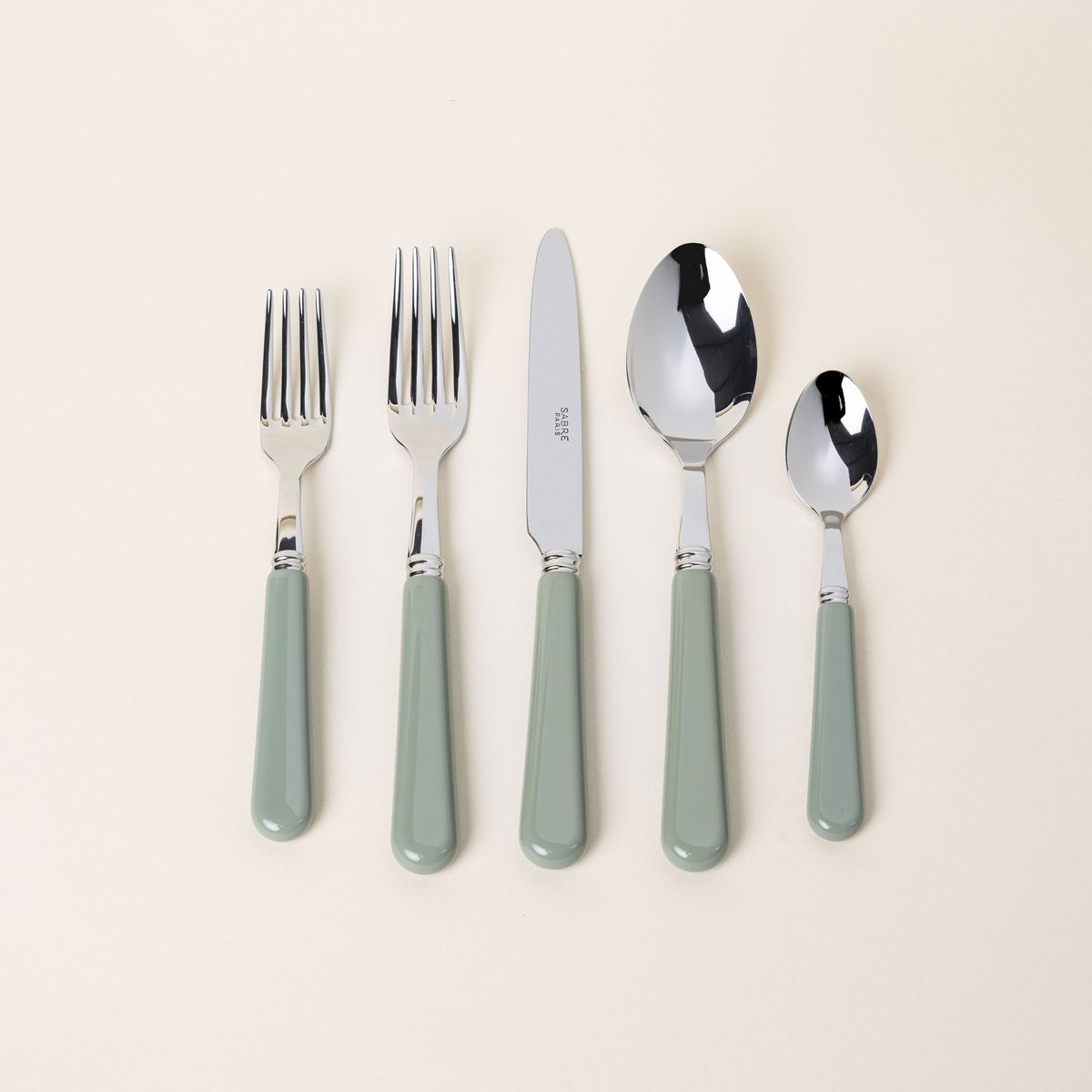 A five piece flatware set with shiny utensils and matte sage green handles