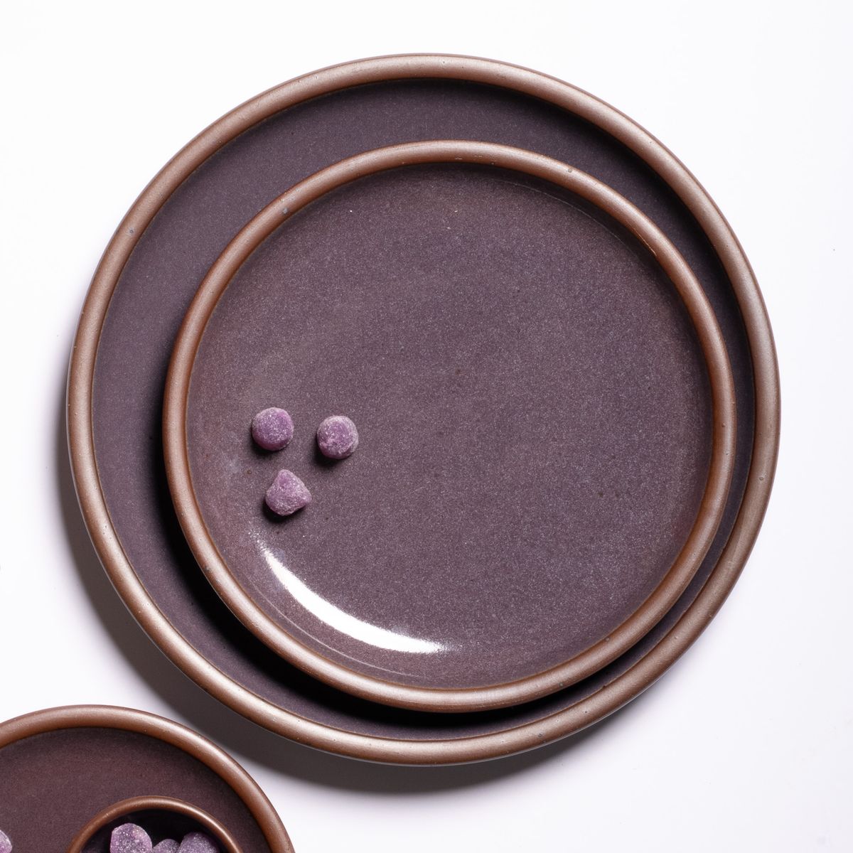 A medium sized plate and a dinner plate stacked together in a purple color with a glowing sheen and 3 gumdrops.