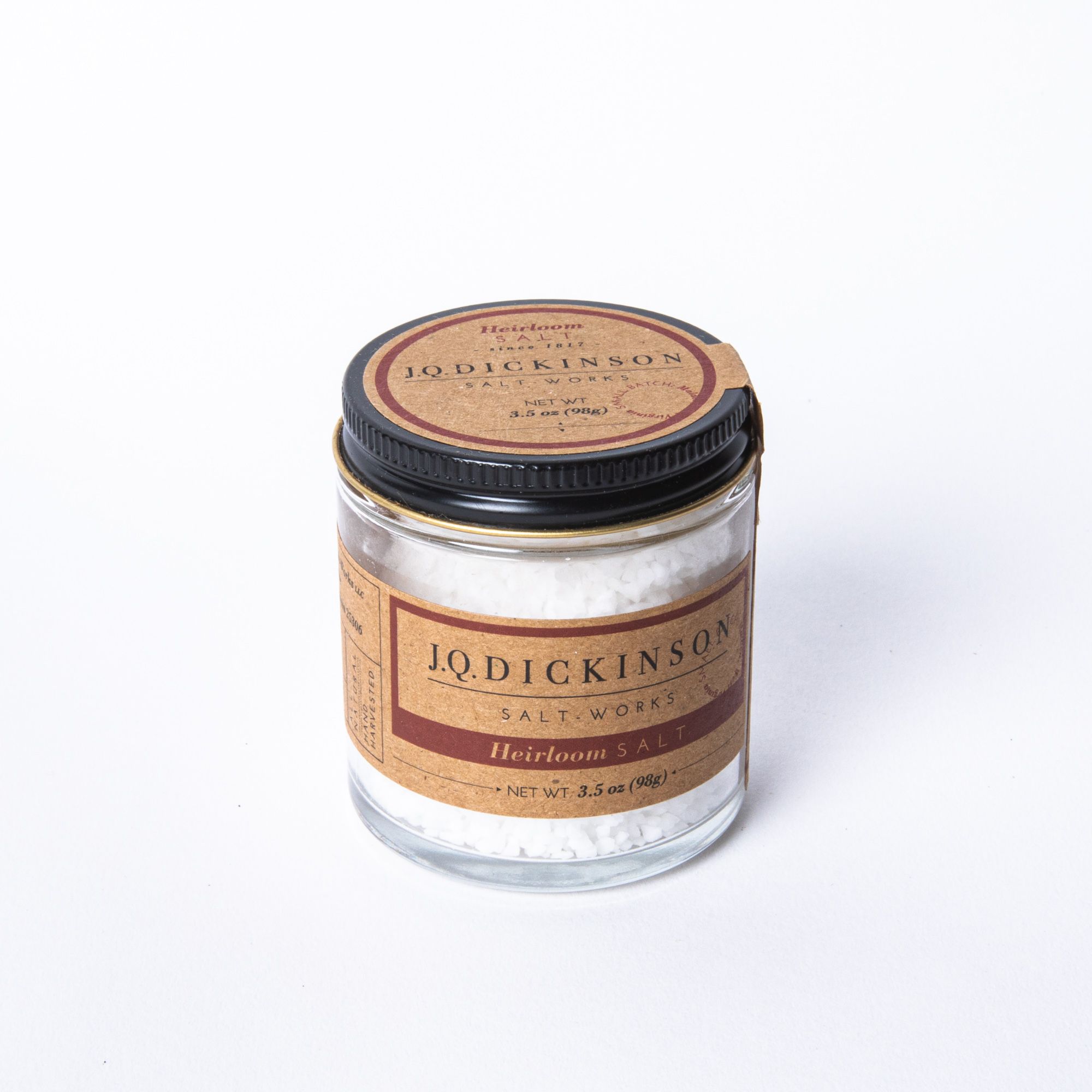 A short jar filled with salt with a kraft brown label and black lid