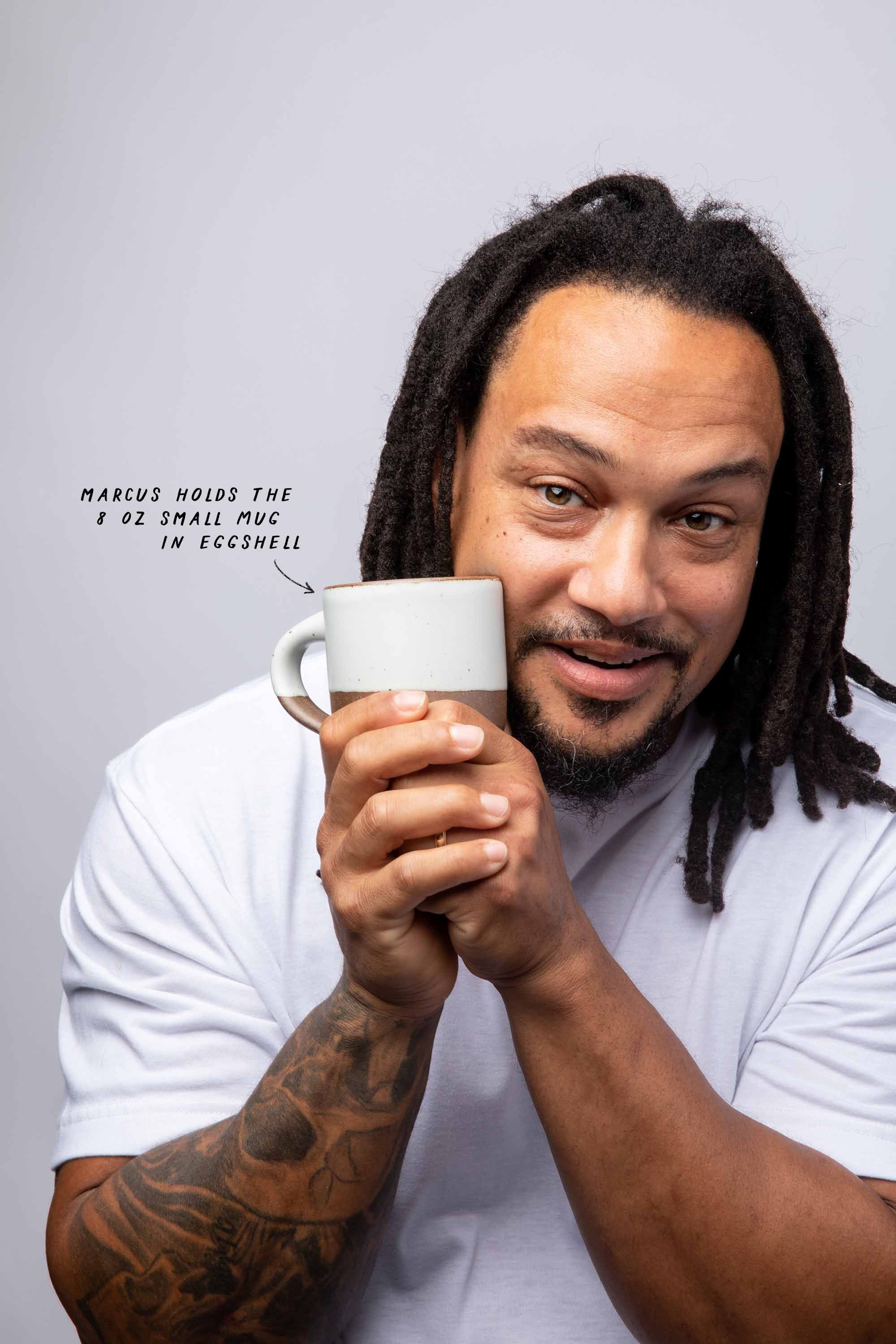Marcuz holds the 8 oz Small Mug in Eggshell up to his cheek